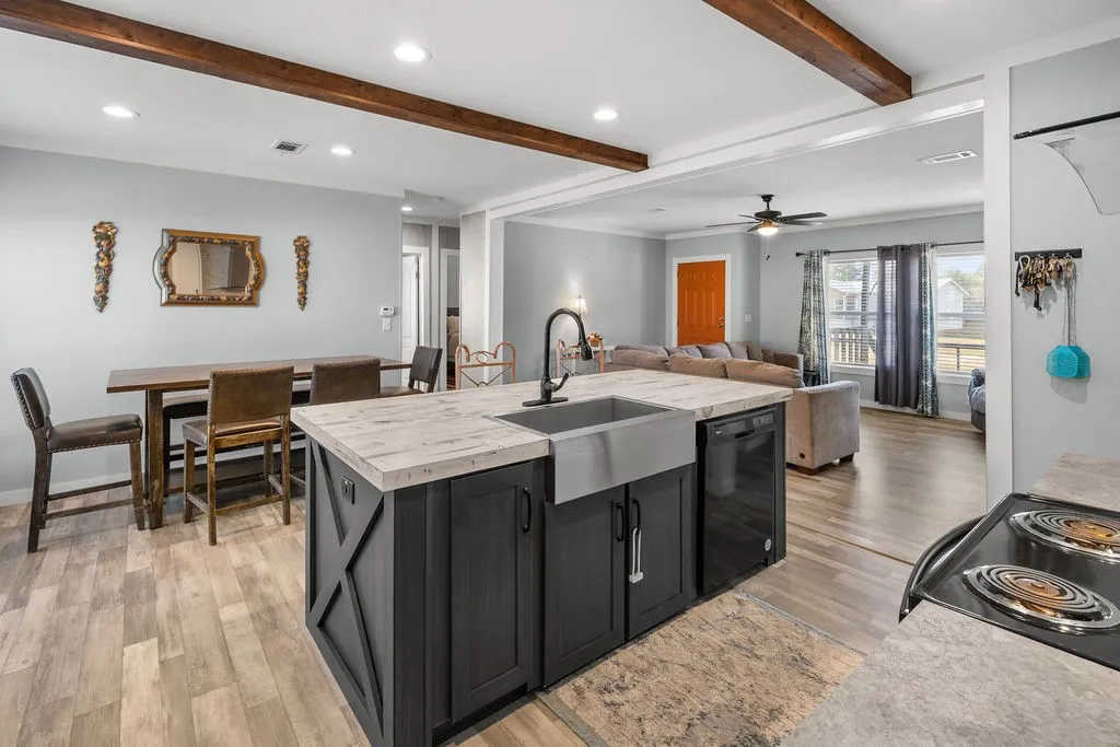 Kitchen island with a farmhouse sink, black cabinetry, and light-toned countertops