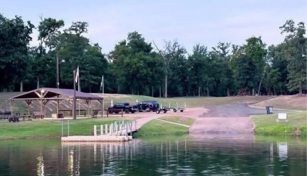 Waterfront property featuring a covered pavilion, floating dock, concrete boat ramp, and extensive treeline