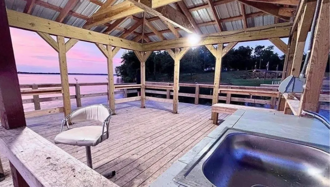 Covered dock with wood decking, built-in sink, and waterfront access