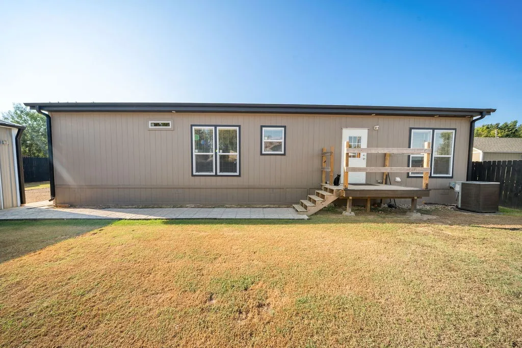 Exterior featuring horizontal siding, multiple windows, a rear entry deck with steps, and a concrete paver walkway