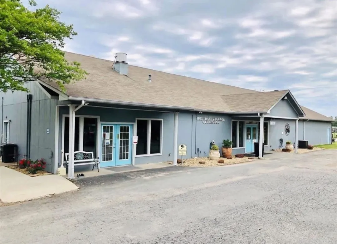 Single-story commercial building with light blue siding, multiple entrance points, and a prominent gable roof