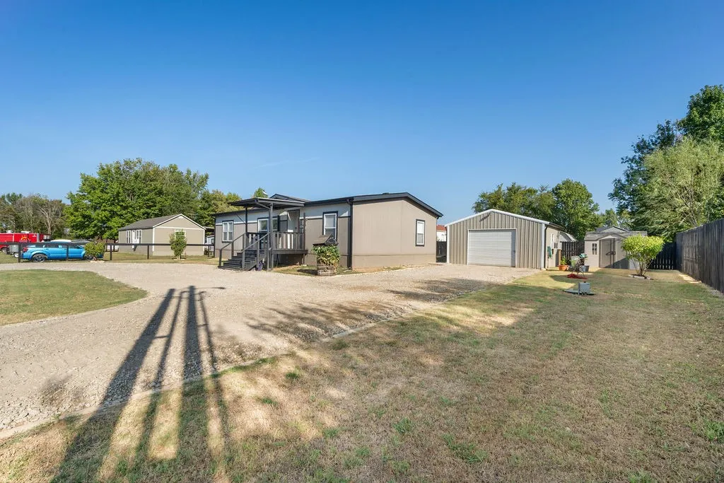 Expansive gravel driveway, large detached garage, private wood fencing, and additional storage shed