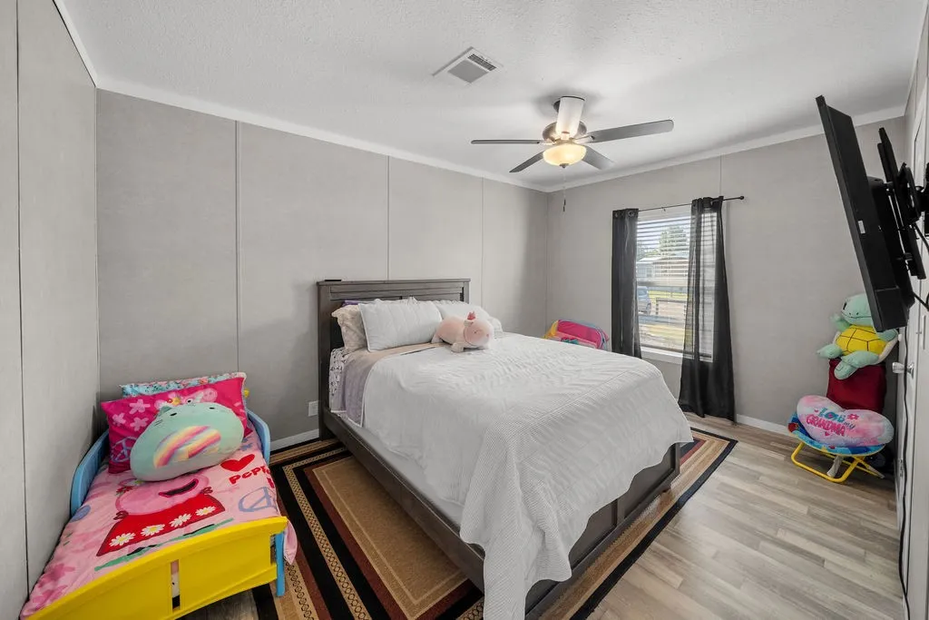 Wood-finish flooring with a ceiling fan and overhead lighting