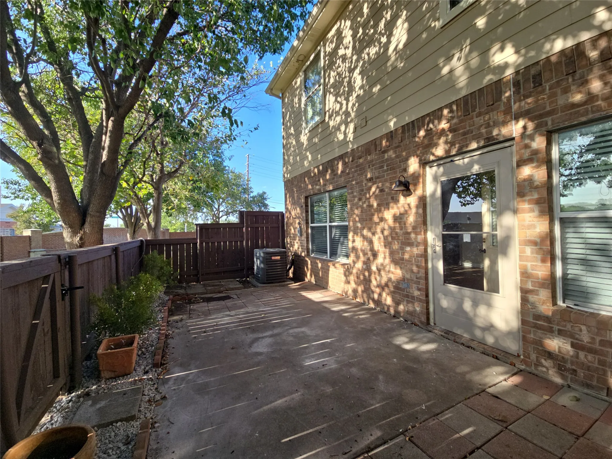 Private patio with wood fencing, brick and siding exterior, and mature trees