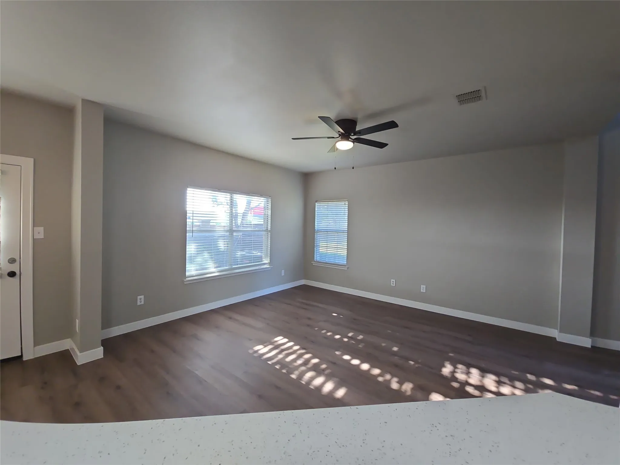 Spacious interior with wood-finish flooring, neutral paint, and multiple windows