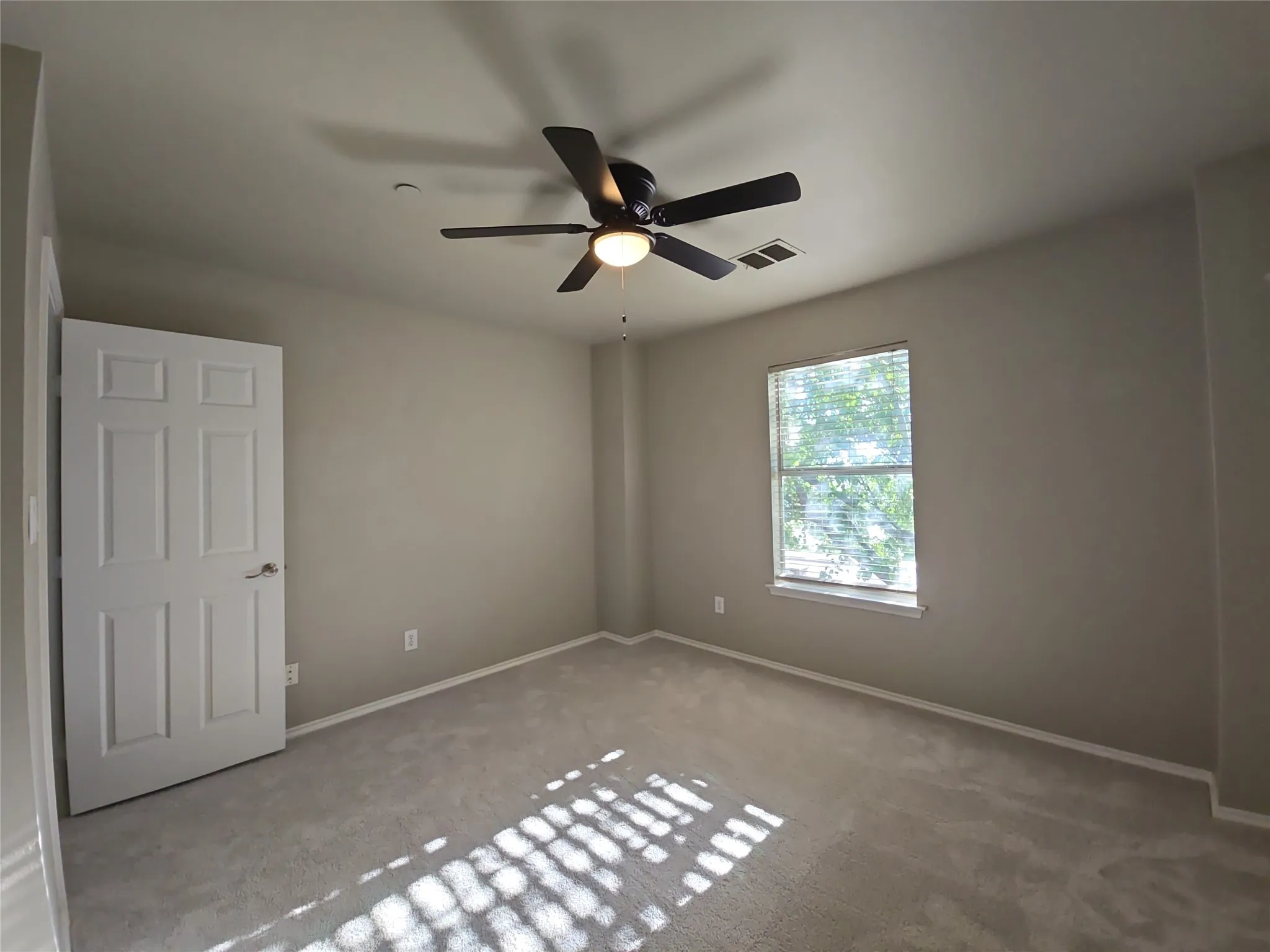 Neutral wall paint, light-toned carpet, ceiling fan with integrated lighting, window with blinds, six-panel interior door