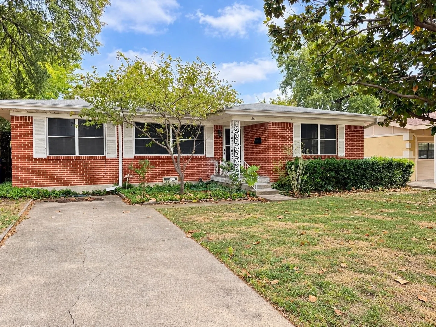 Brick exterior with white window shutters and a front porch featuring decorative metal railing