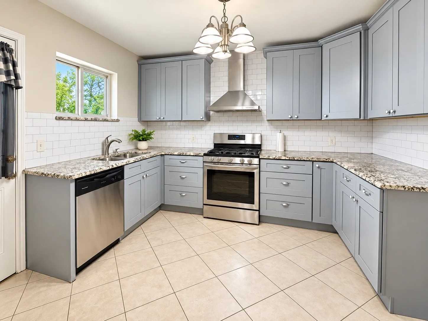 Stainless steel appliances, light gray cabinetry, granite countertops, subway tile backsplash, and tile flooring