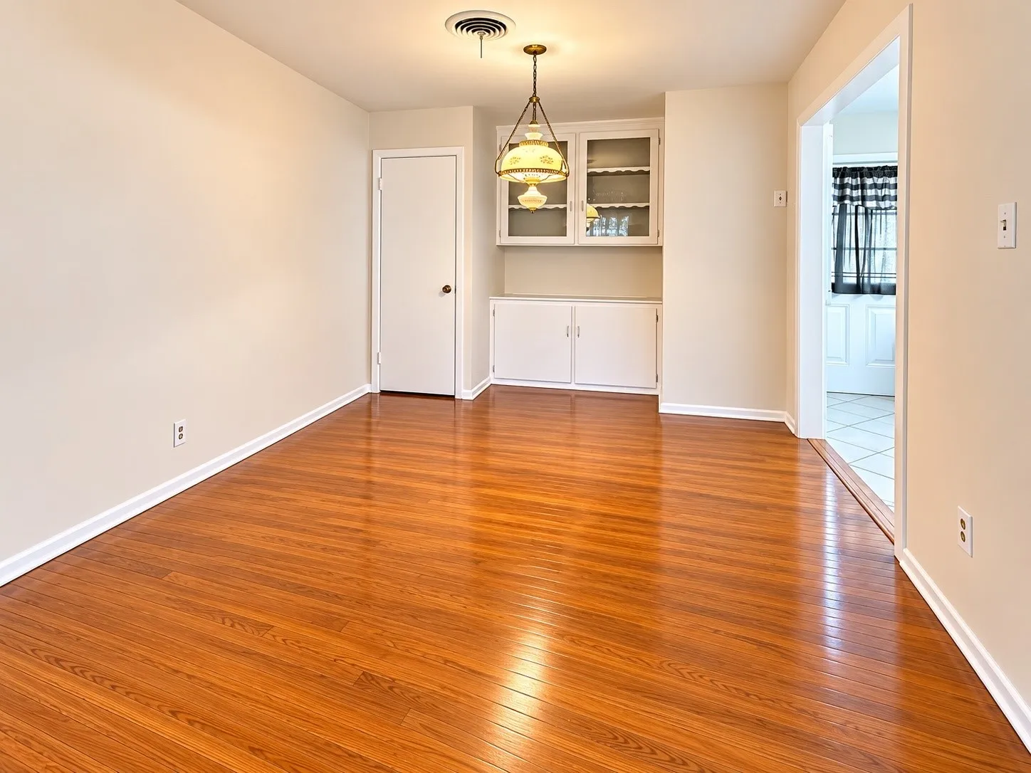 Wood-finish flooring, built-in cabinetry with glass-front uppers, and an overhead light fixture