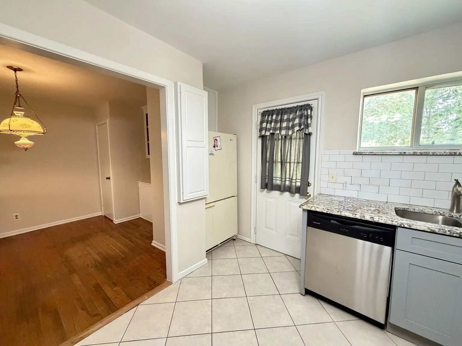 Kitchen featuring granite-style countertops, subway tile backsplash, and stainless steel dishwasher