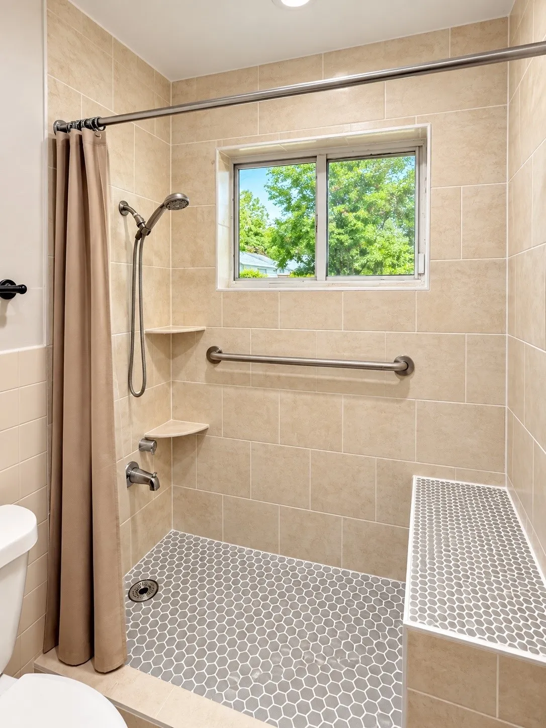 Shower featuring large format tiled walls, a built-in bench, and hexagonal floor tiling