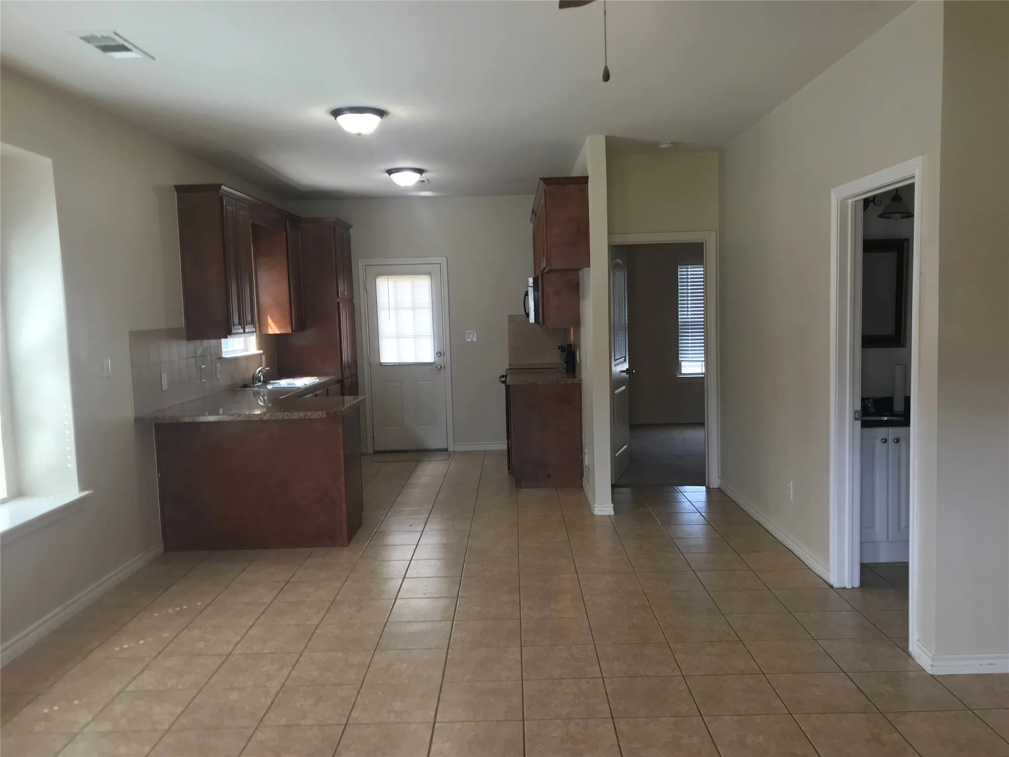 Kitchen featuring wood-finish cabinetry, stone-look countertops, and a tile backsplash
