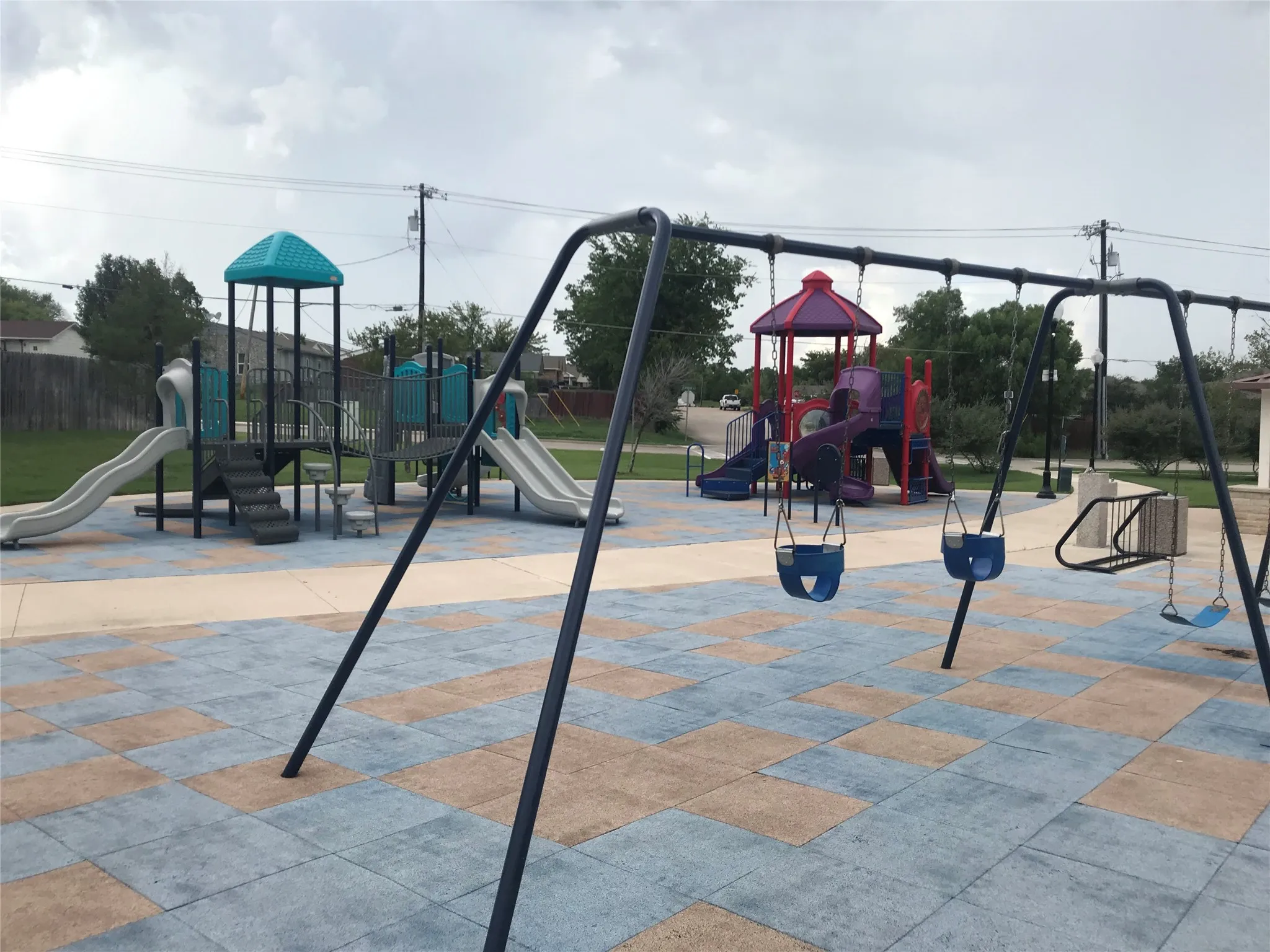 Playground area featuring two multi-level play structures, multiple slides, and a swing set
