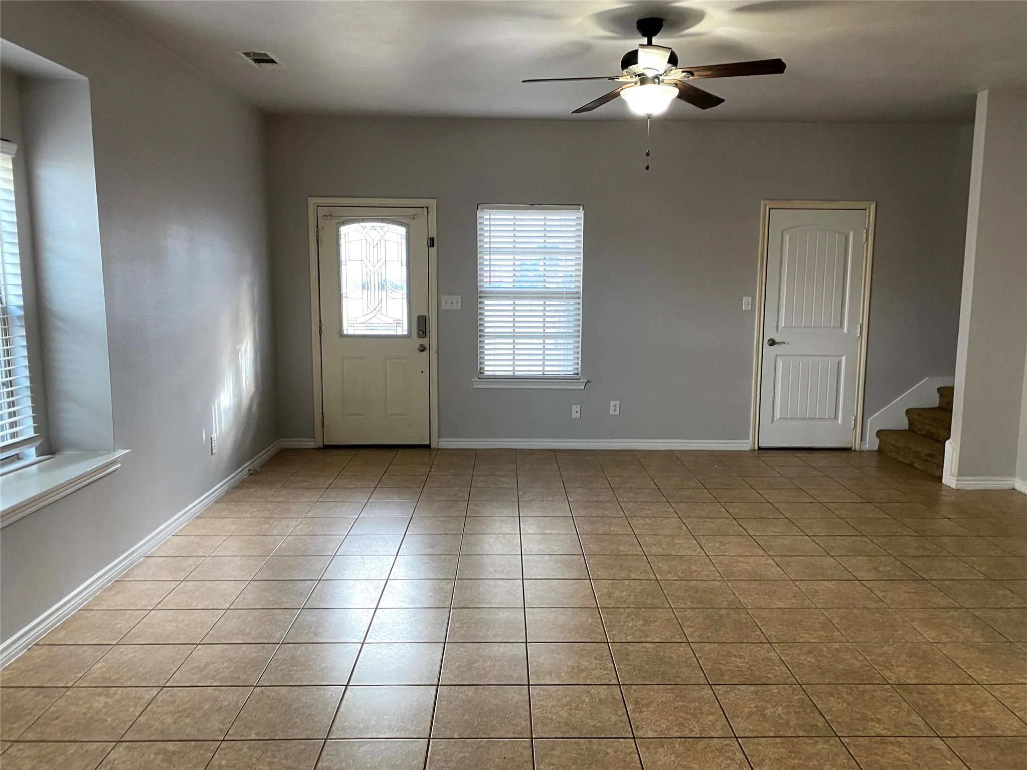 Tile flooring, ceiling fan with integrated lighting, window with blinds, white trim, and a paneled door