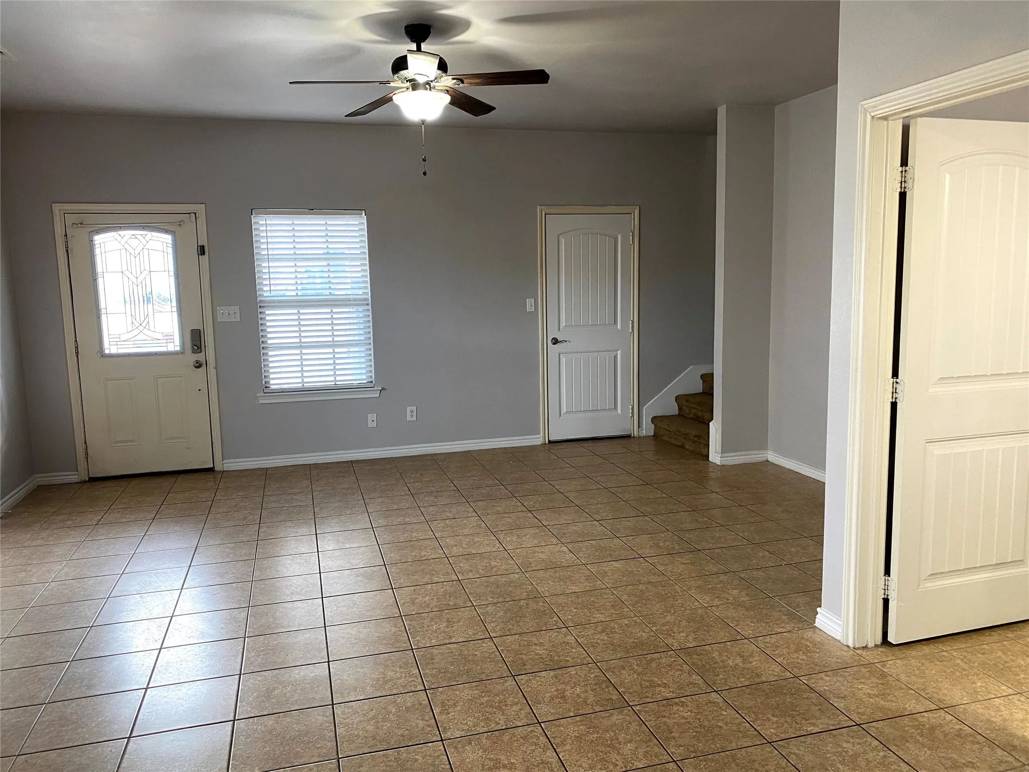 Tile flooring, ceiling fan with integrated lighting, paneled interior doors, and a window with blinds