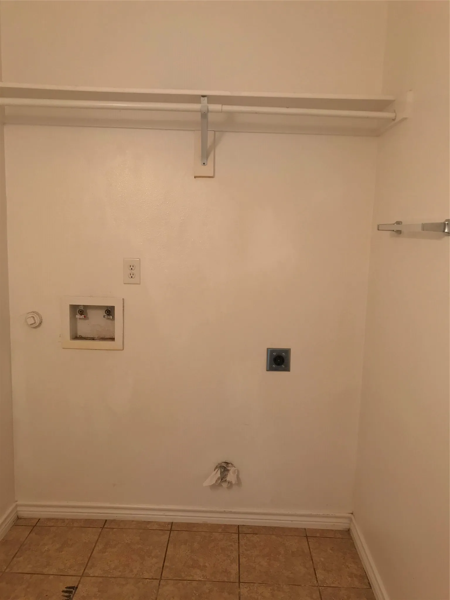 Laundry area featuring tile flooring, washer hookups, dryer hookups, and a built-in shelf with a hanging rod
