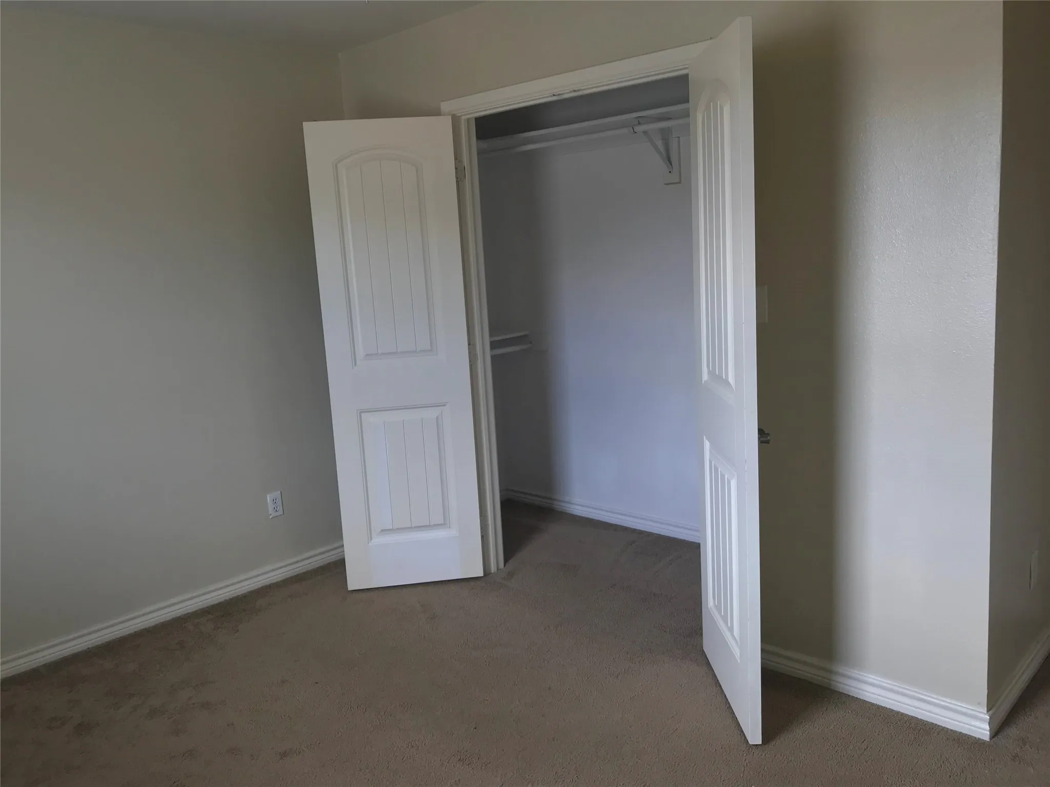 Carpeted flooring with painted walls, white trim, and a closet featuring bi-fold doors