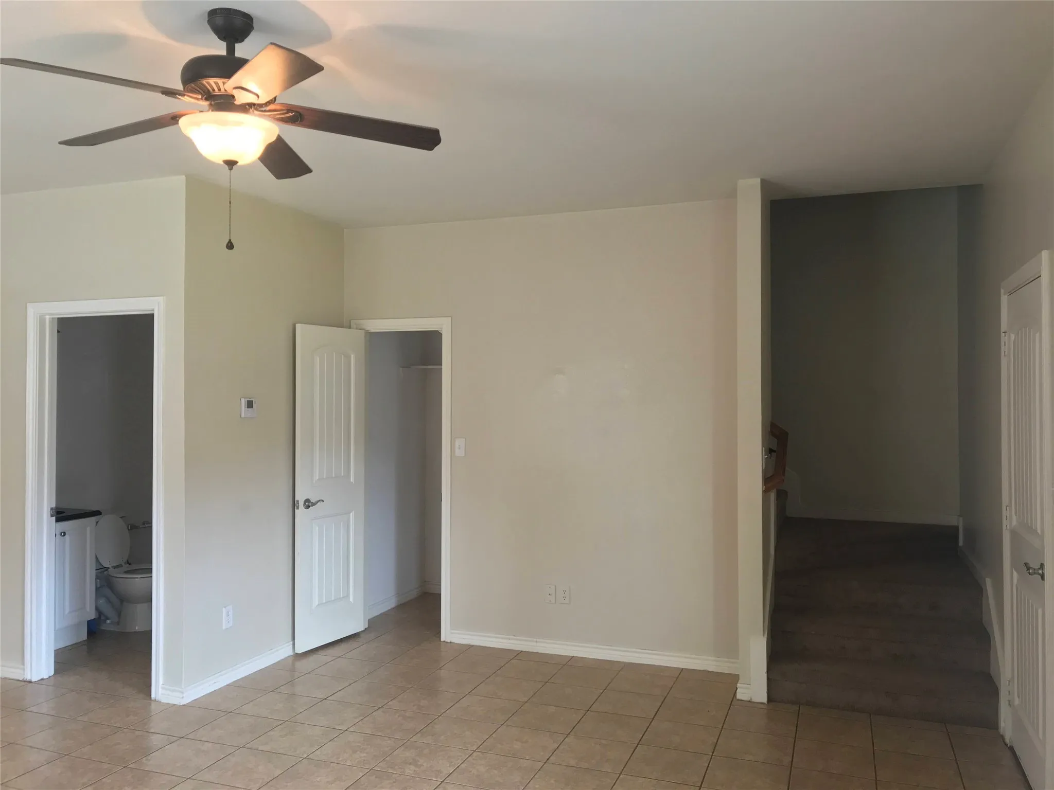 Tiled flooring throughout, ceiling fan with integrated lighting, a full-lite interior door, and a built-in closet