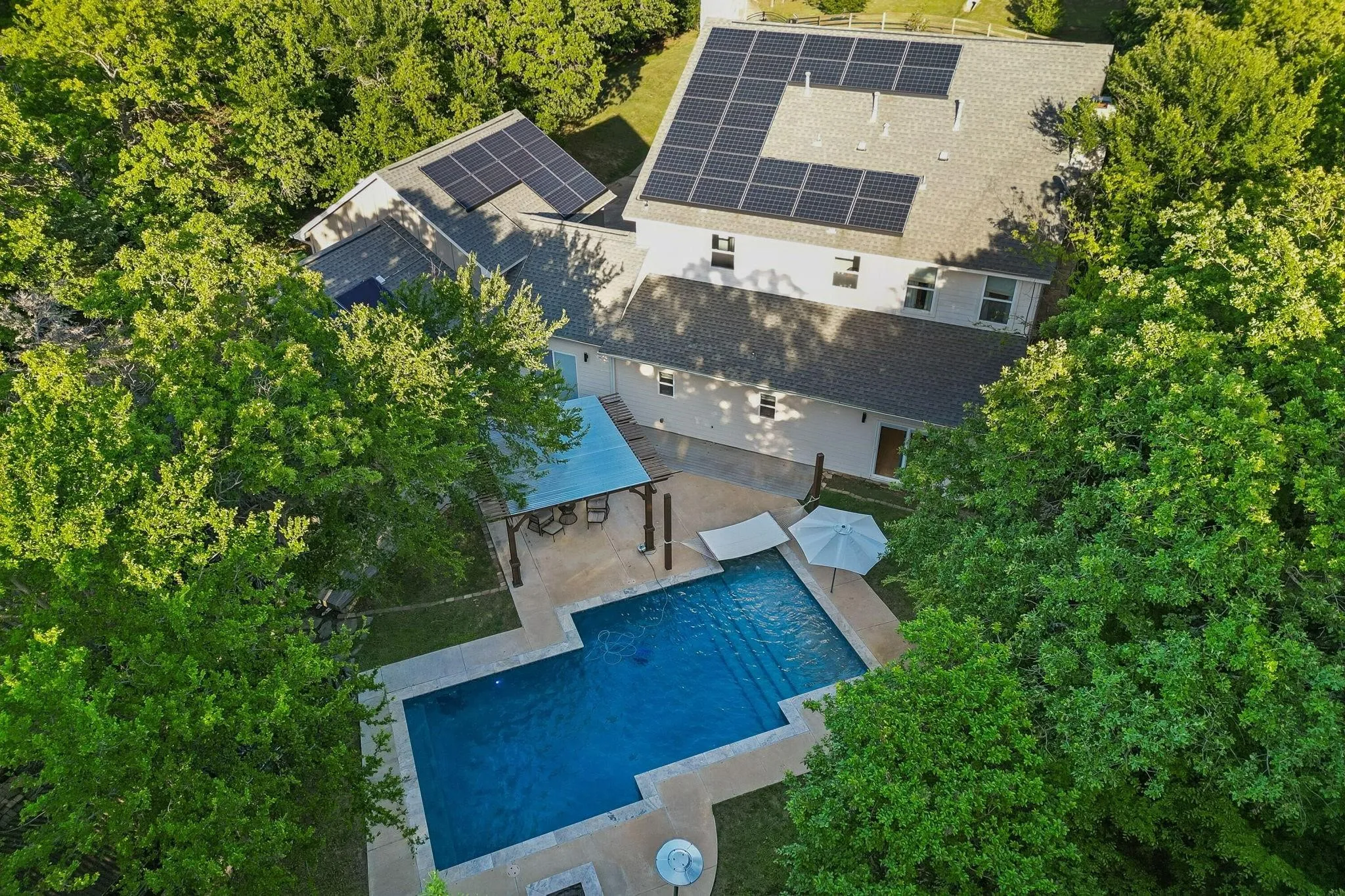 Sparkling swimming pool surrounded by mature trees, creating a private and peaceful backyard retreat.