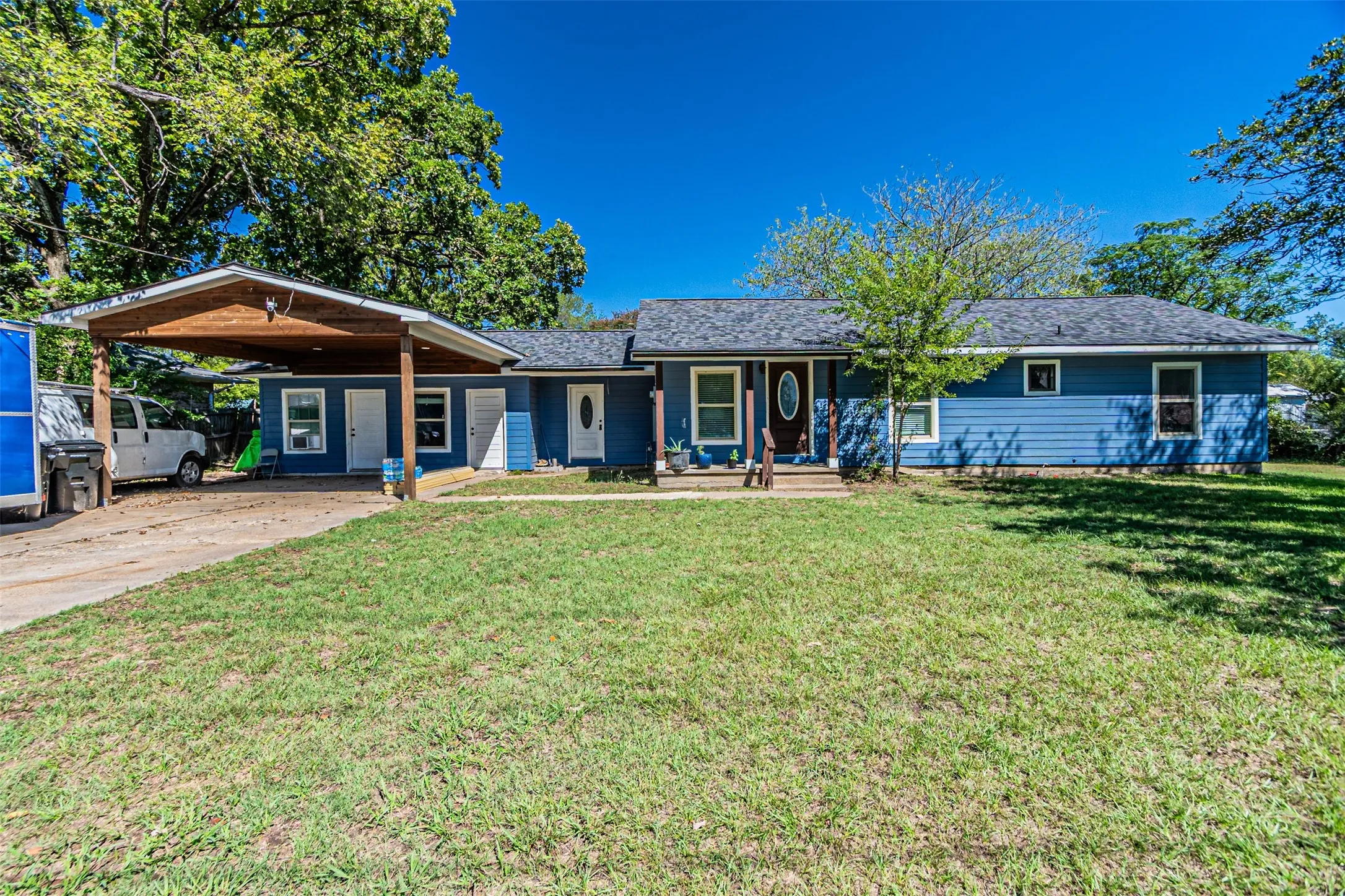 Blue siding exterior with a dark shingle roof, covered carport, and a front entry porch