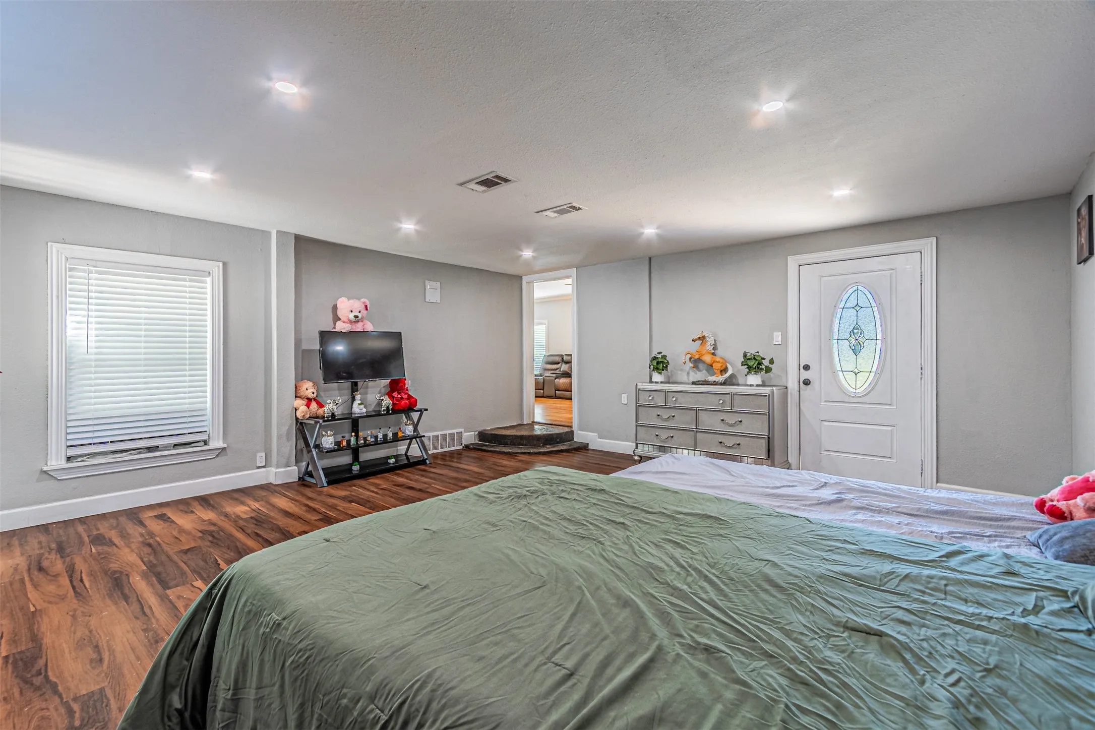 Wood-finish flooring, recessed ceiling lighting, light gray wall color, white trim, and a white entry door with a decorative glass insert