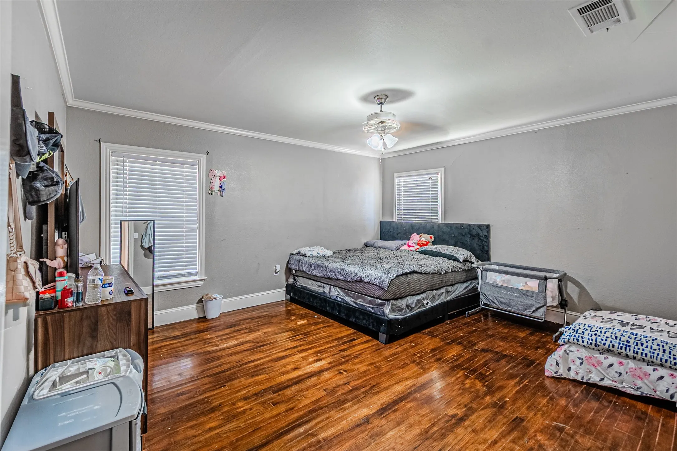Hardwood-finish flooring, white trim, ceiling fan light fixture, and multiple windows
