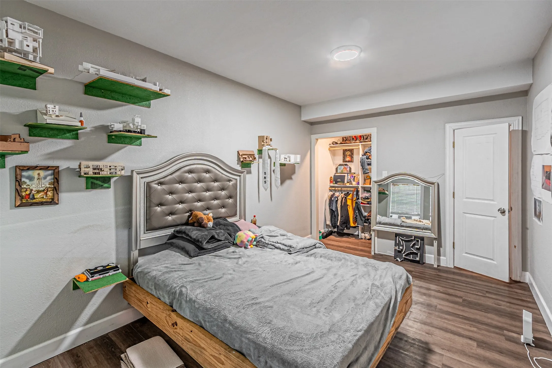 Recessed ceiling light, wood-finish flooring, built-in shelving, paneled interior door, and an open closet with organizational shelving