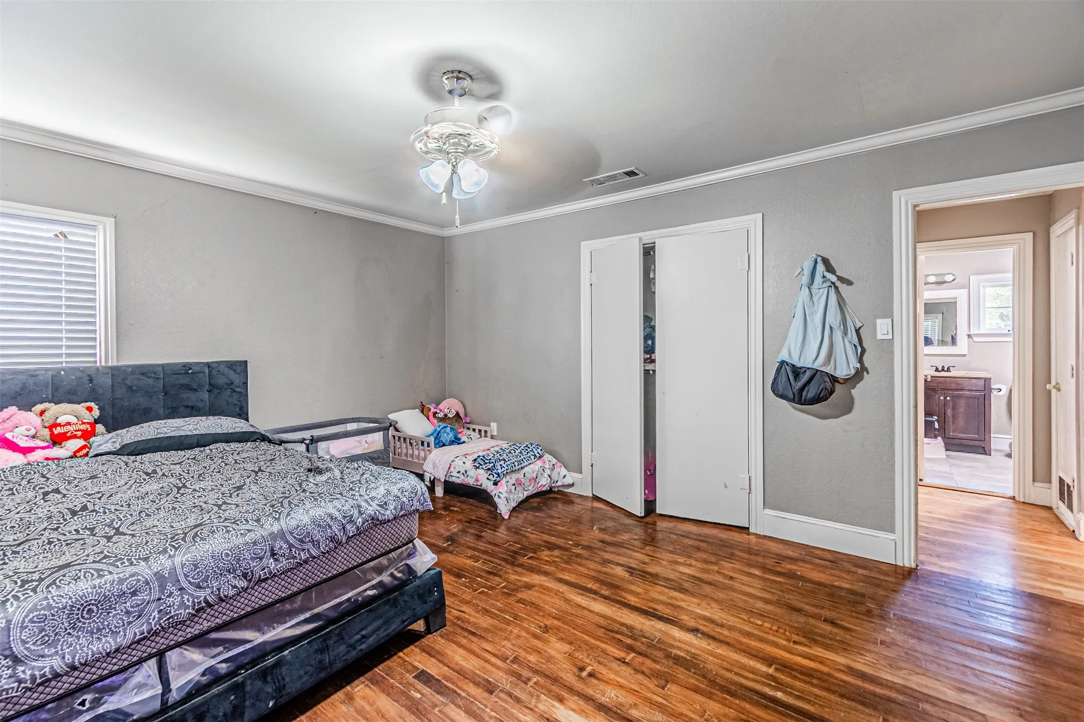 Hardwood flooring, crown molding, white trim, window with blinds, and ceiling fan with lighting