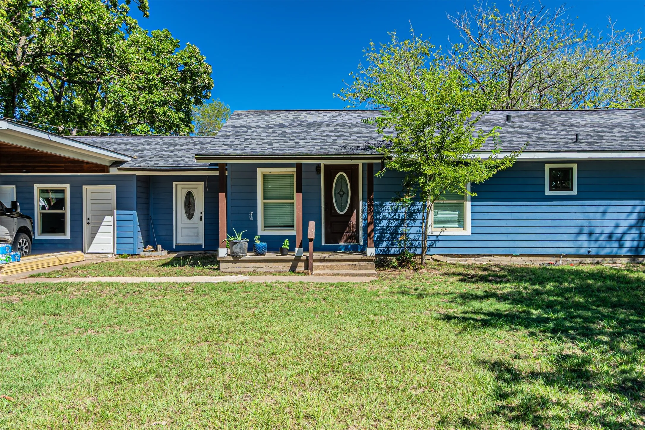 Blue horizontal siding exterior with a dark shingle roof, featuring a covered entry and a secondary white entry door