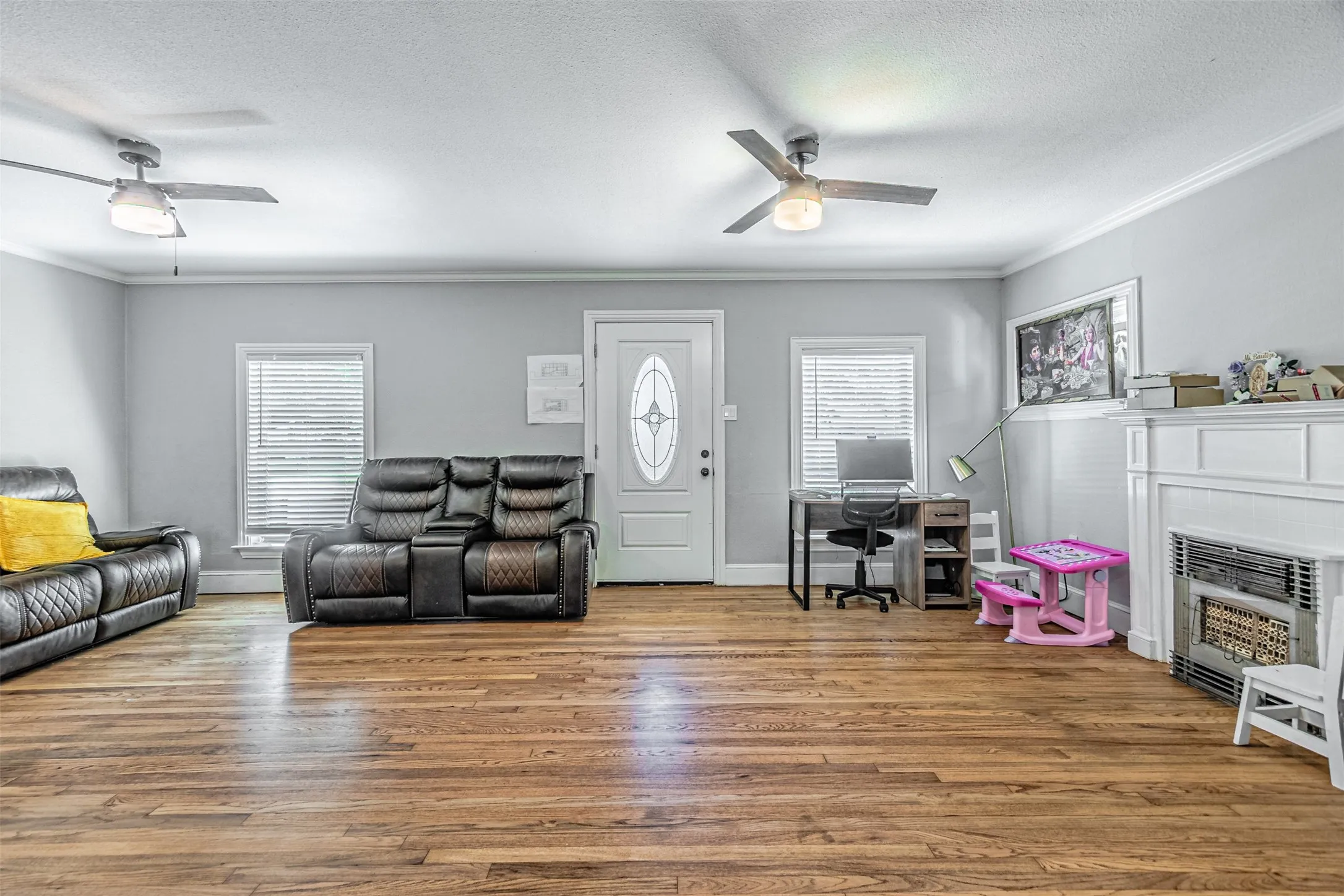 Hardwood flooring, crown molding, white trim, ceiling fans, and a decorative fireplace