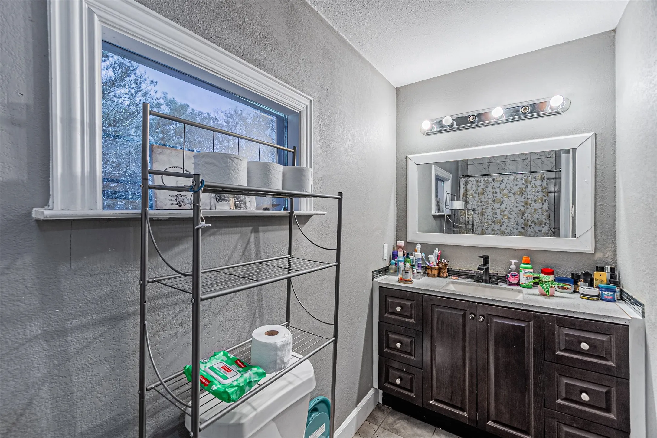 Vanity with dark wood-finish cabinetry, countertop, and an integrated sink with a black faucet