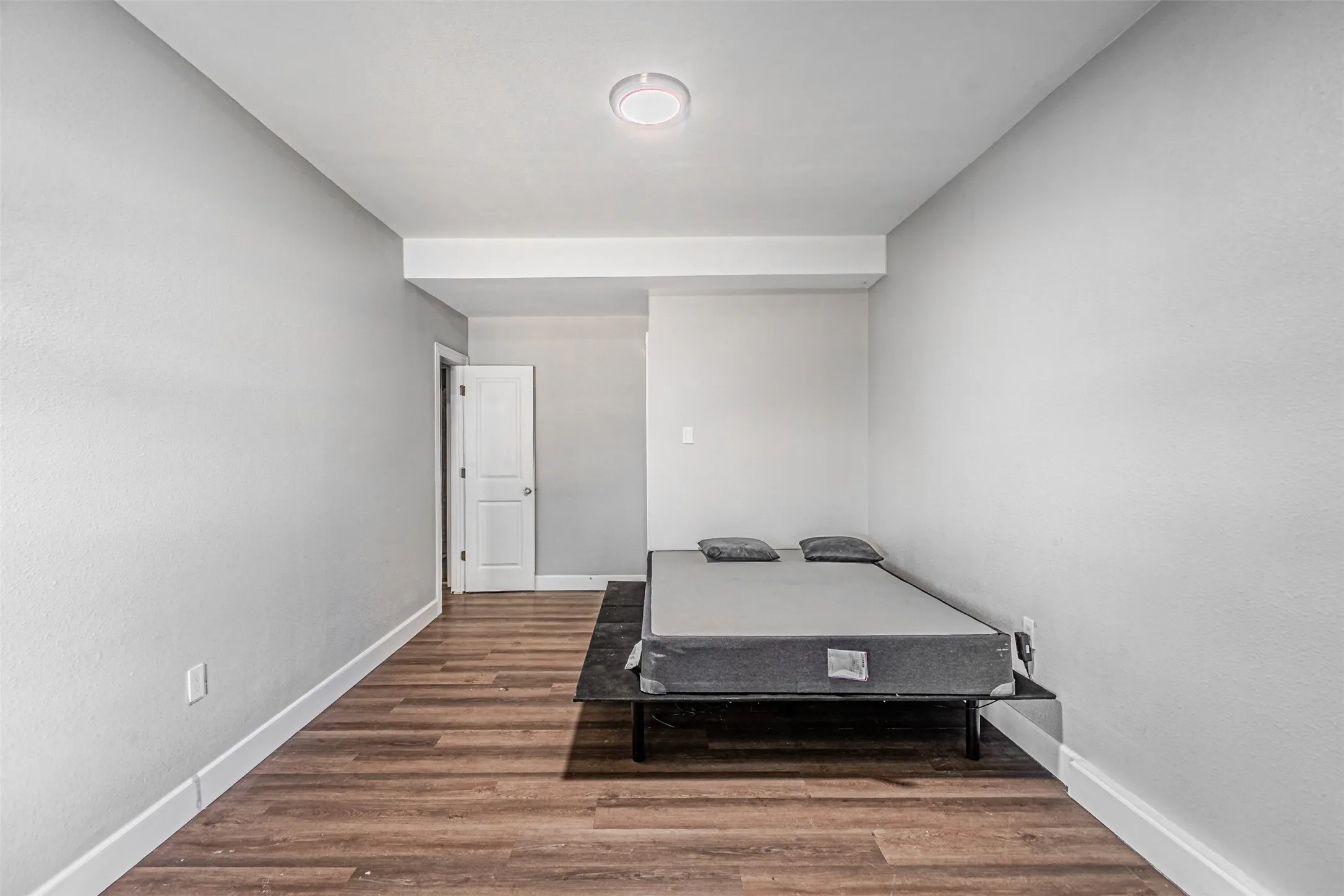 Recessed ceiling light fixture, wood-finish flooring, white trim, and a white interior door