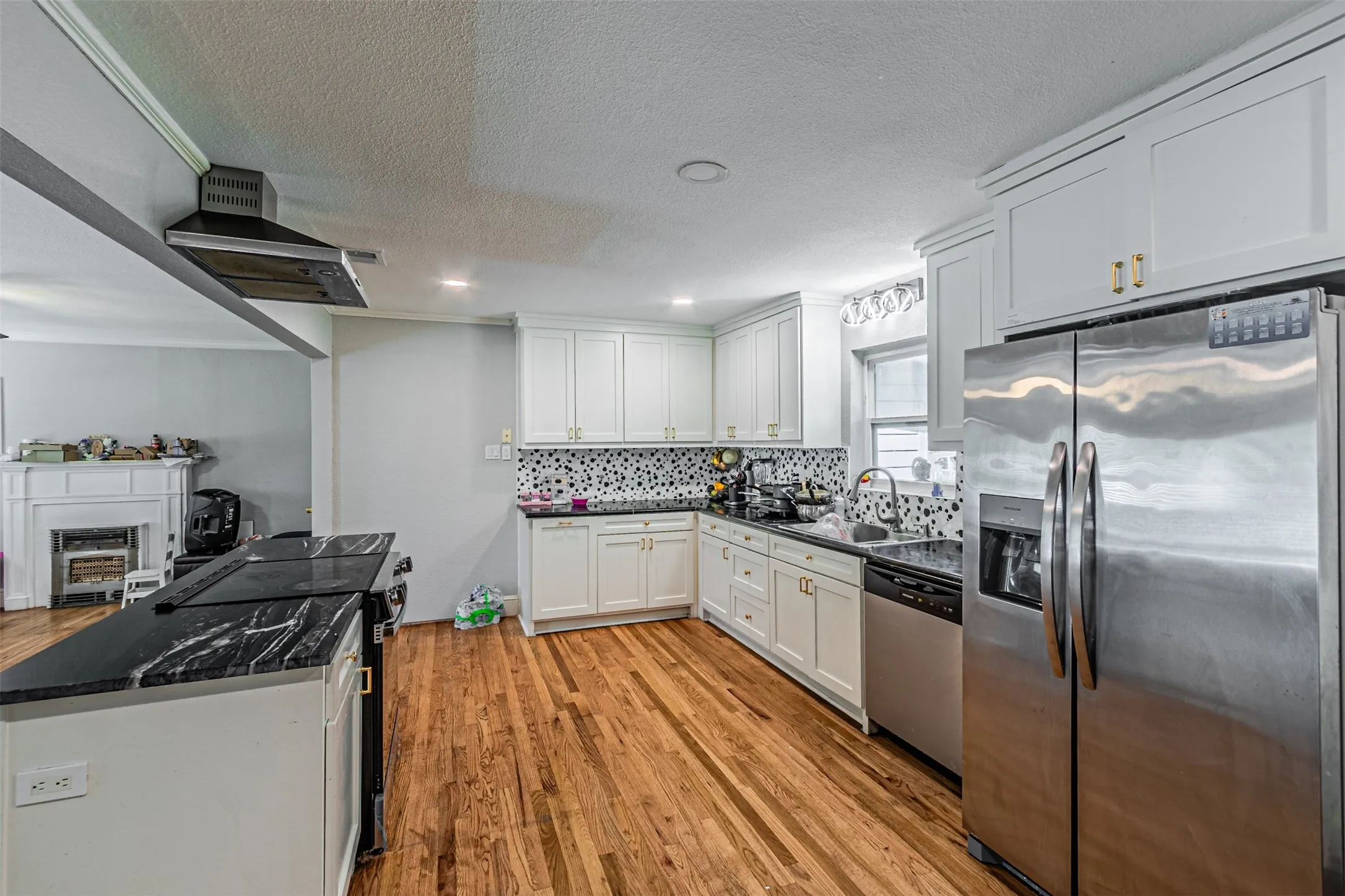 Kitchen featuring white cabinetry, dark countertops, wood-finish flooring, and stainless steel appliances