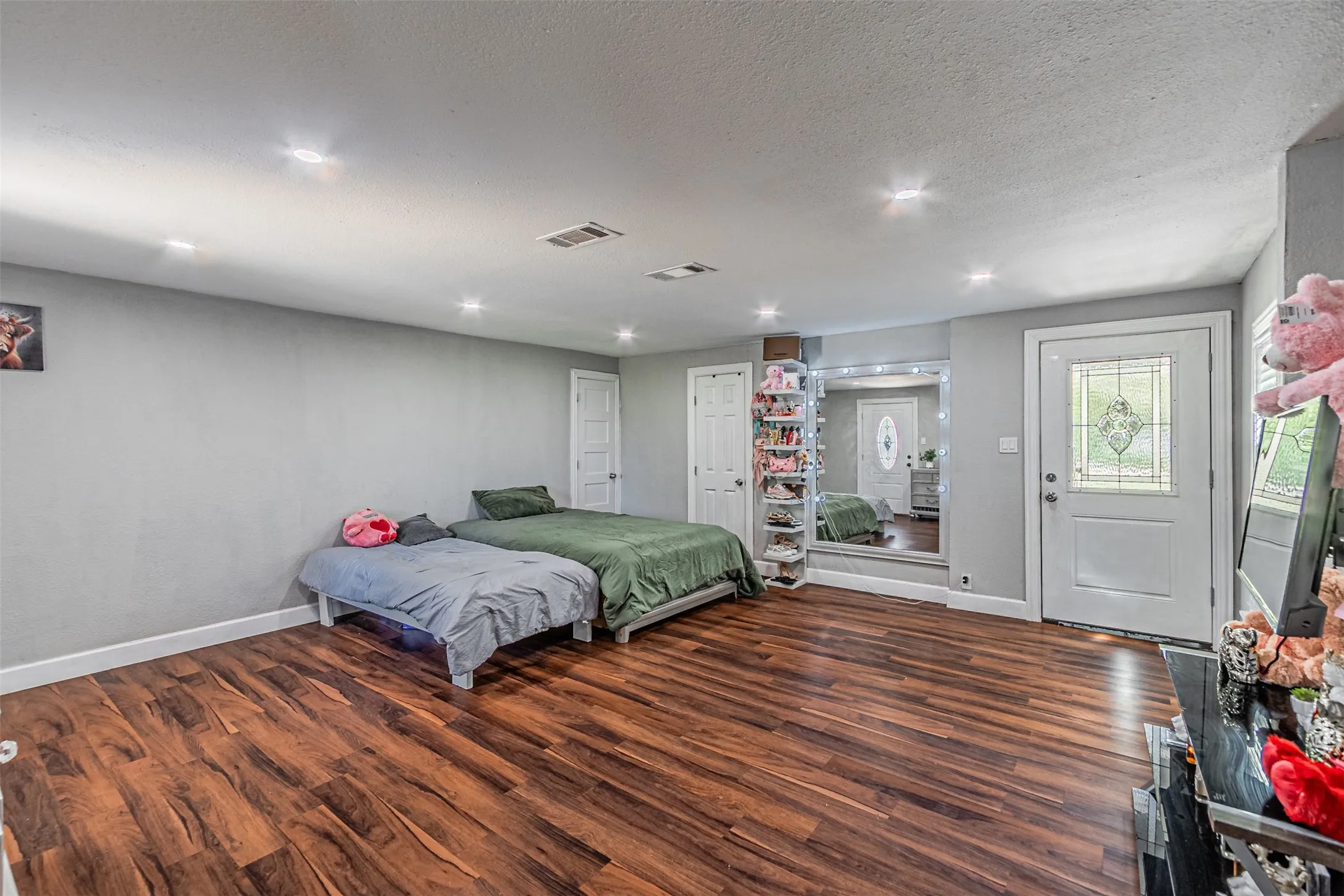 Wood-finish flooring, recessed lighting, and a white paneled door