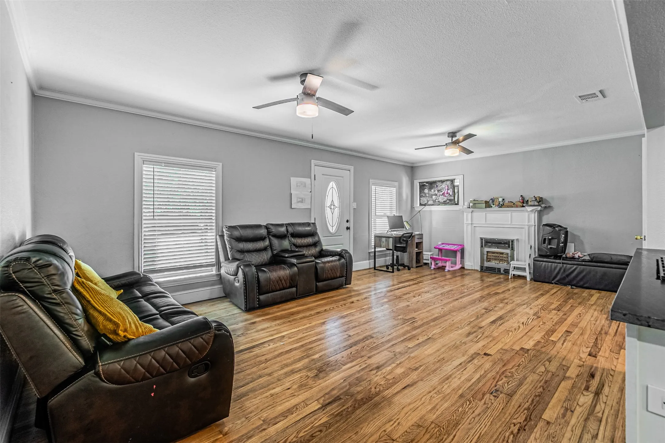 Hardwood flooring, painted walls, white trim, ceiling fans, and a decorative fireplace