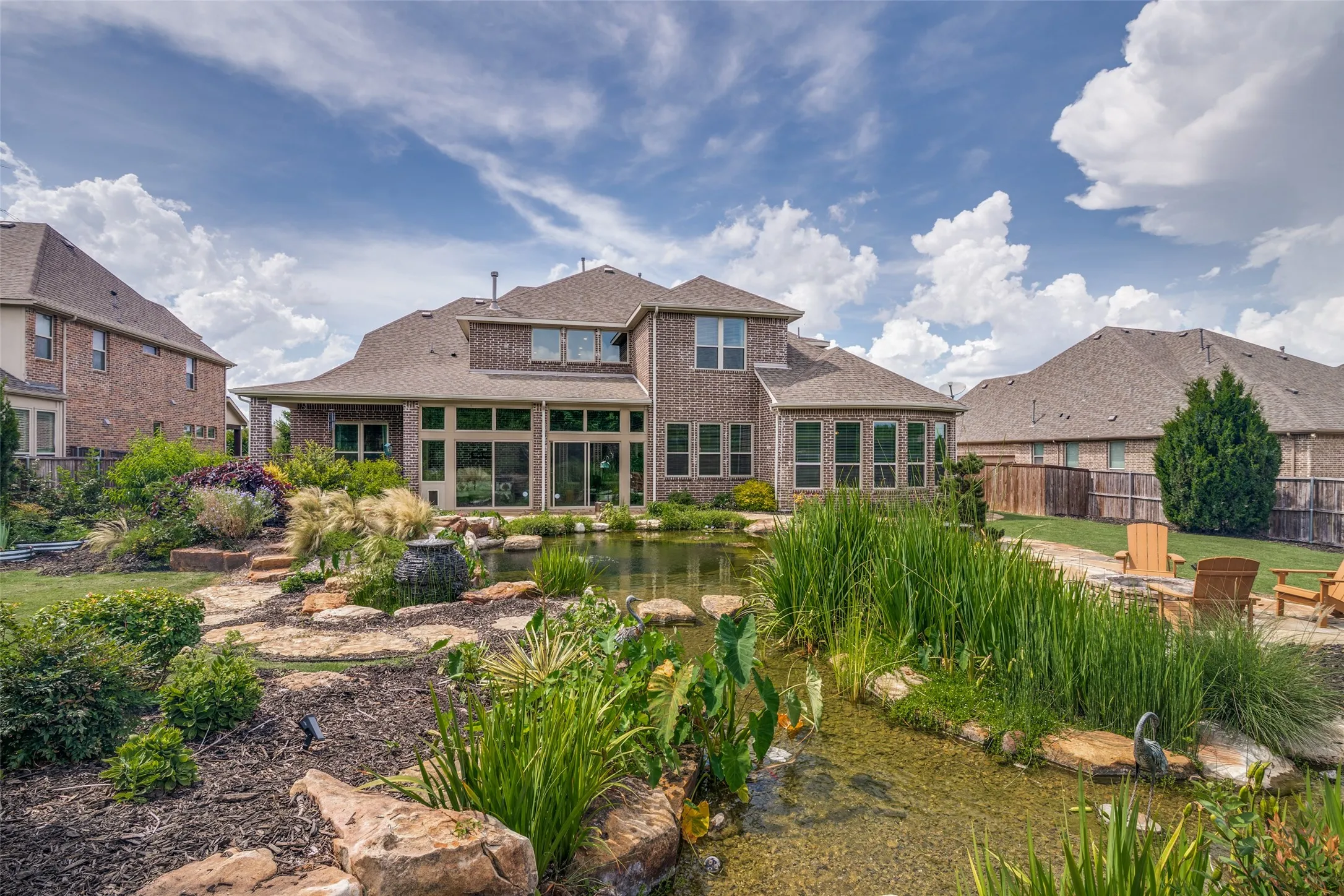 Expansive backyard with a custom water feature, stone-lined pond, flagstone patio, and established landscaping