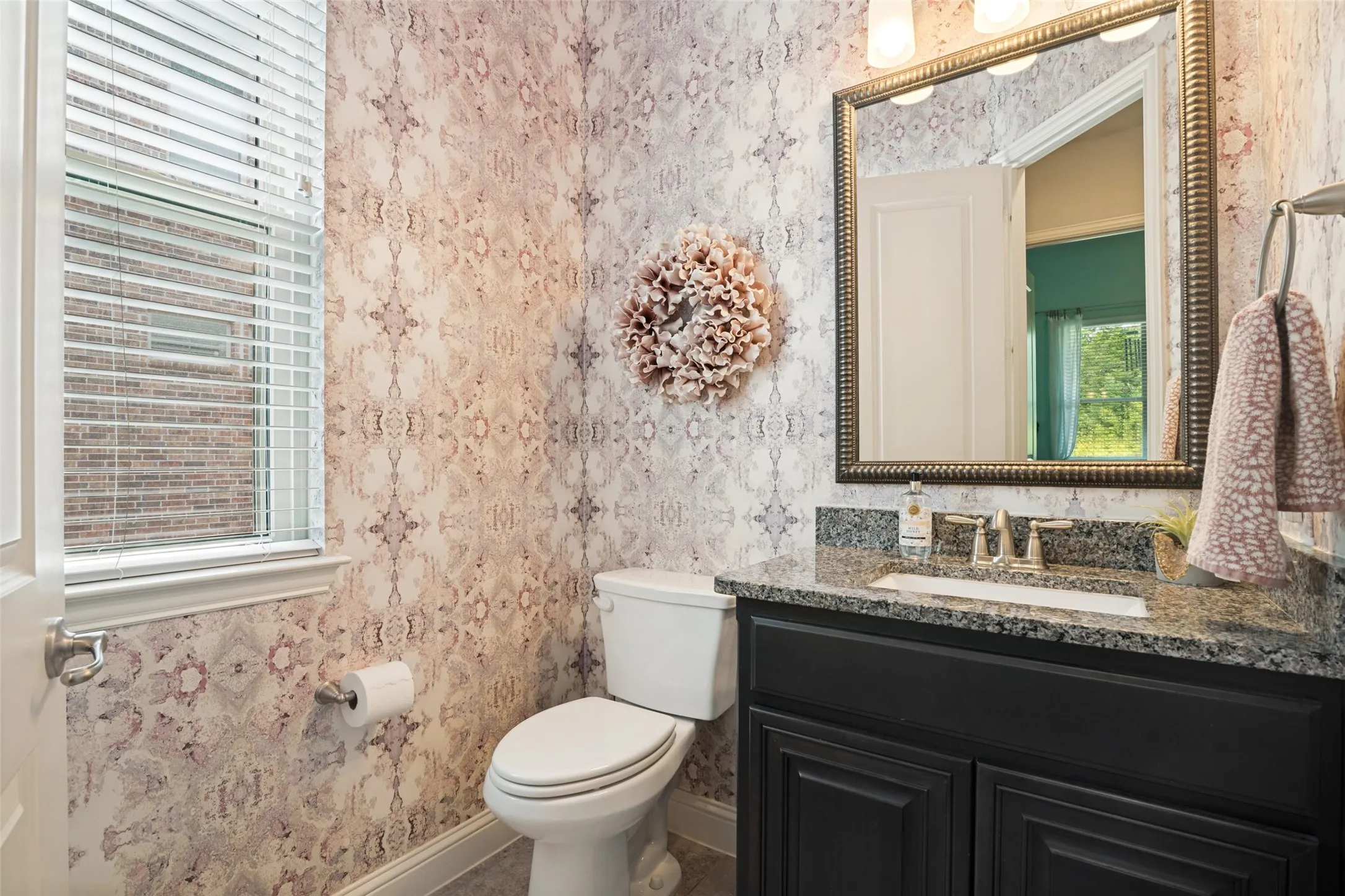 Vanity with a granite countertop, undermount sink, and dark wood cabinetry