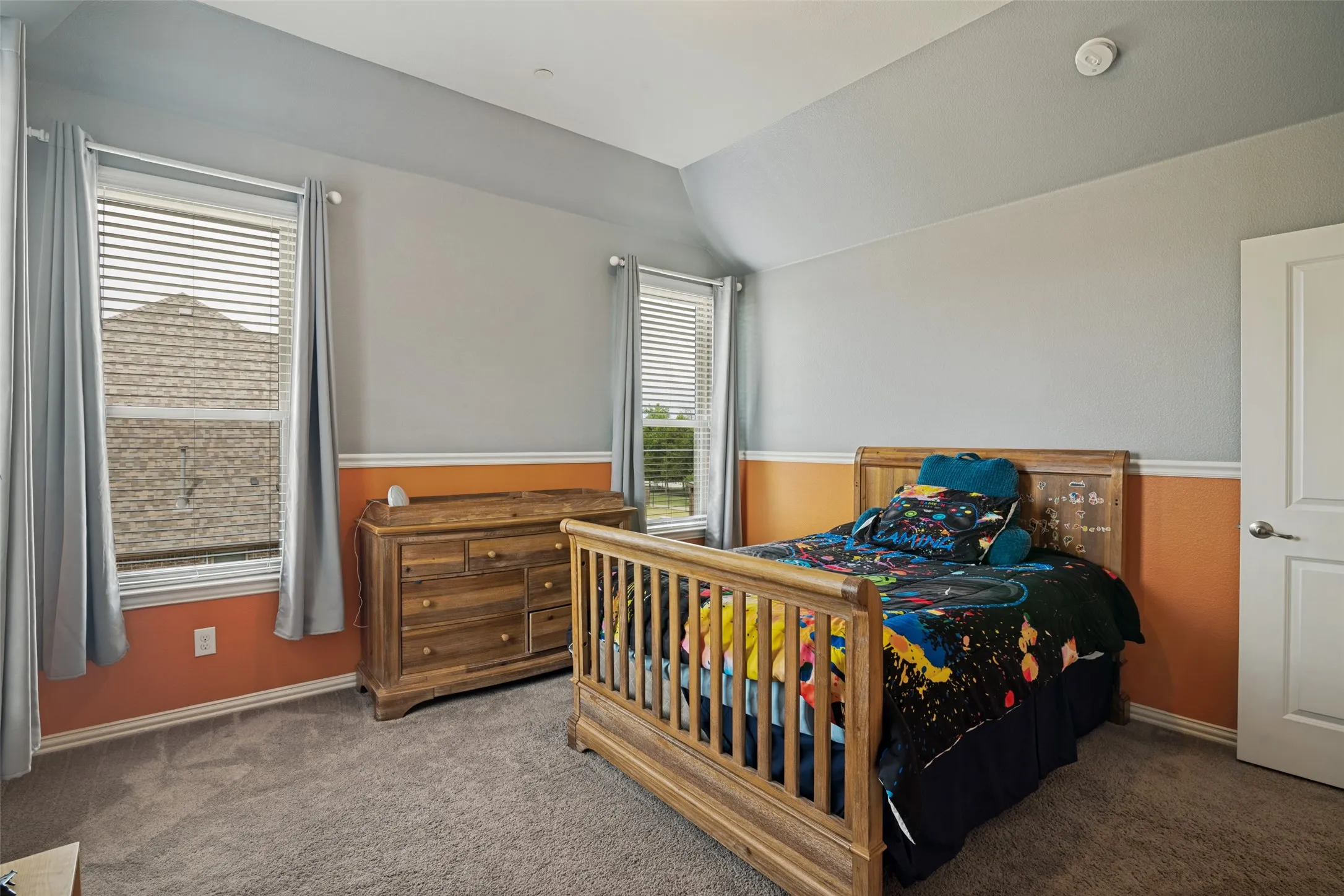Carpeted room with multiple windows, featuring a sloped ceiling and a white door