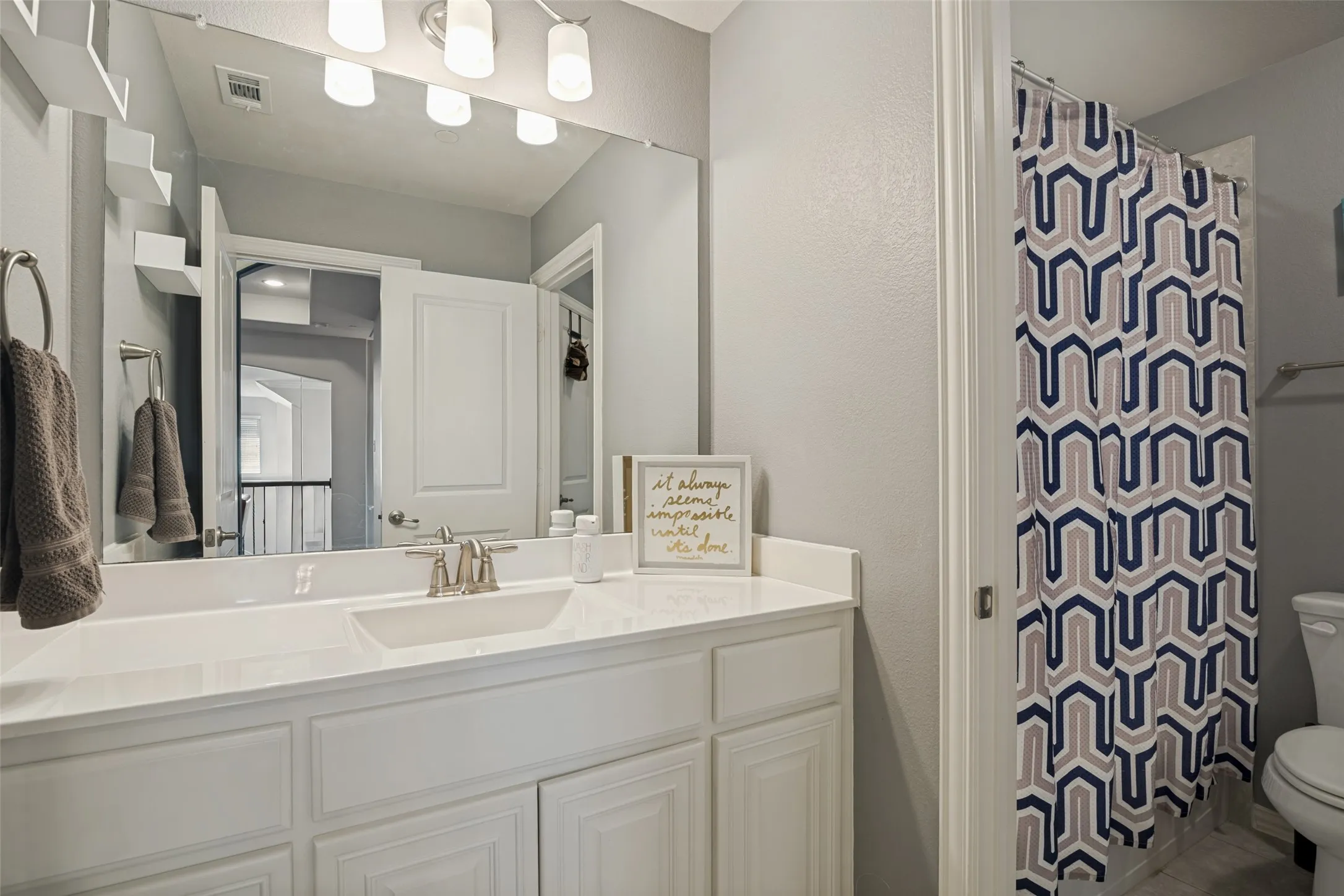 Dual vanity with paneled cabinetry, brushed nickel fixtures, and extensive wall mirror