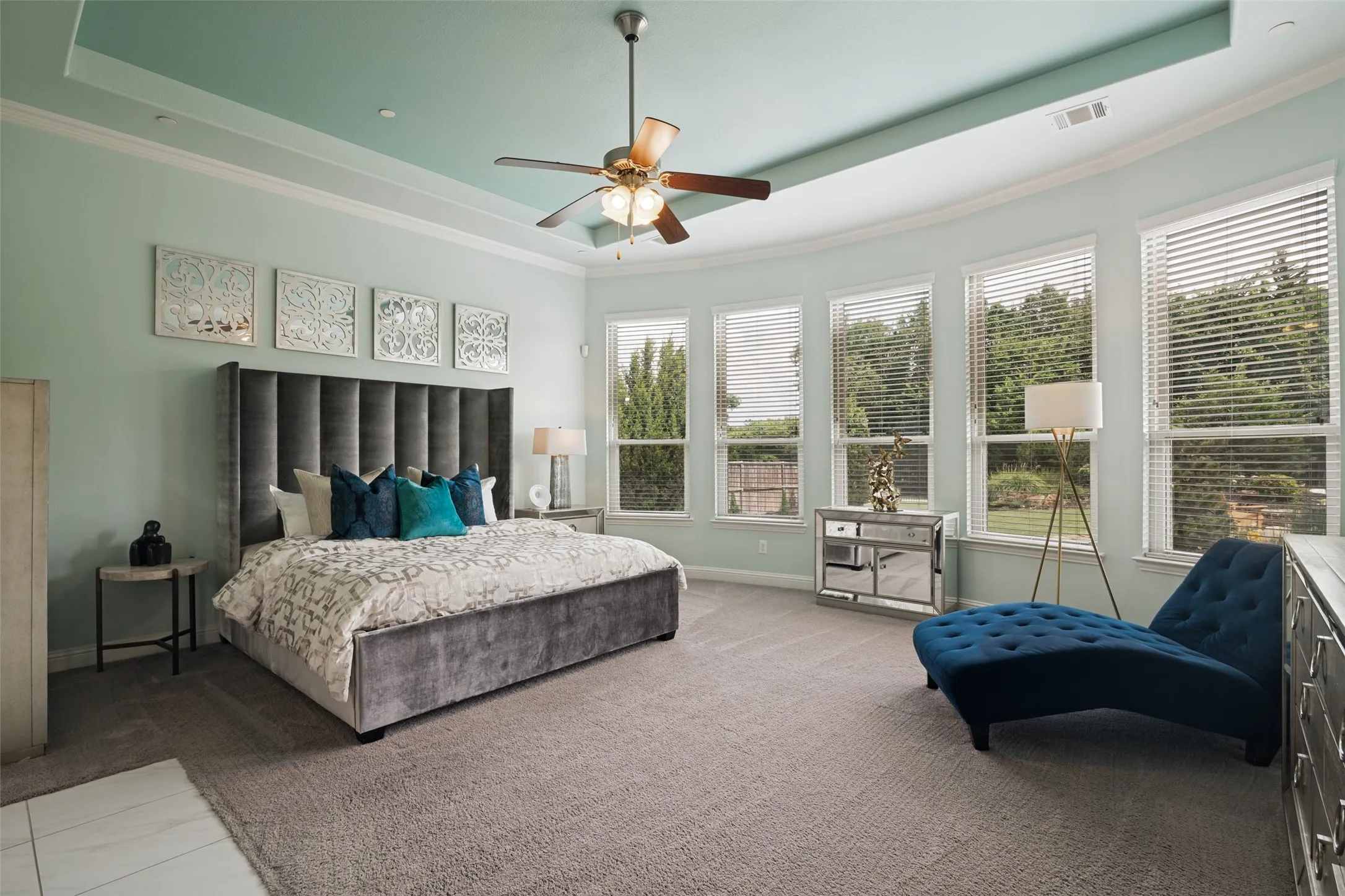 Tray ceiling with crown molding, ceiling fan, carpet flooring, multiple windows, and a tiled entryway
