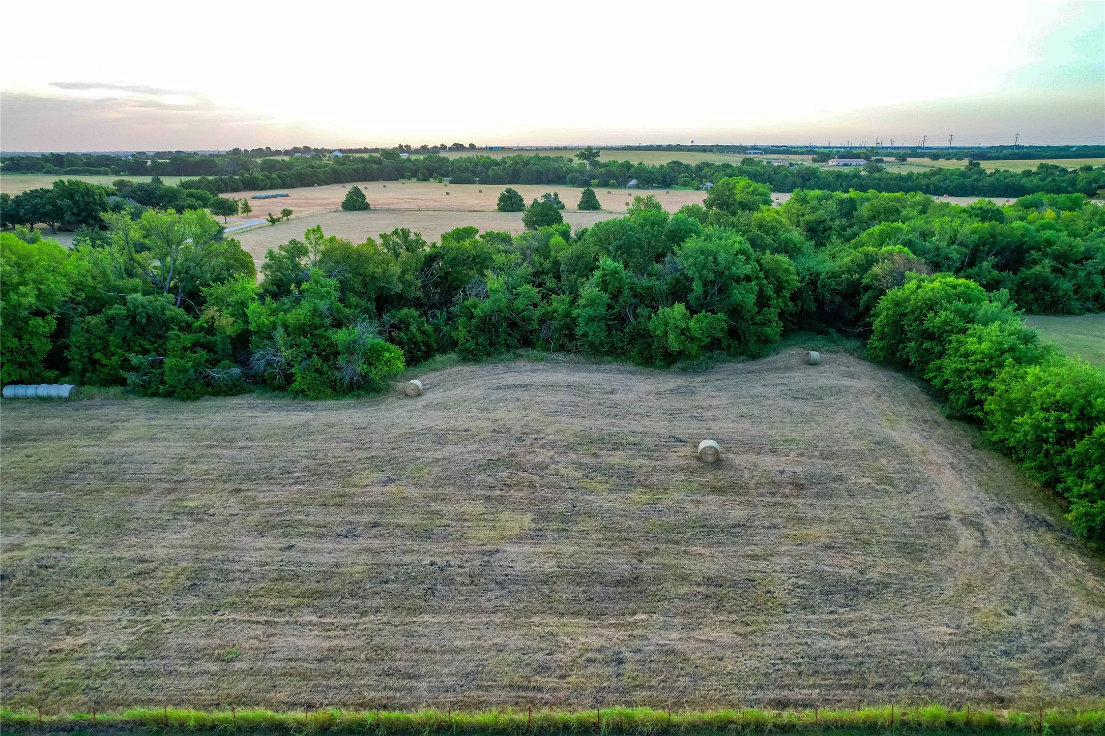 Expansive agricultural field with scattered hay bales