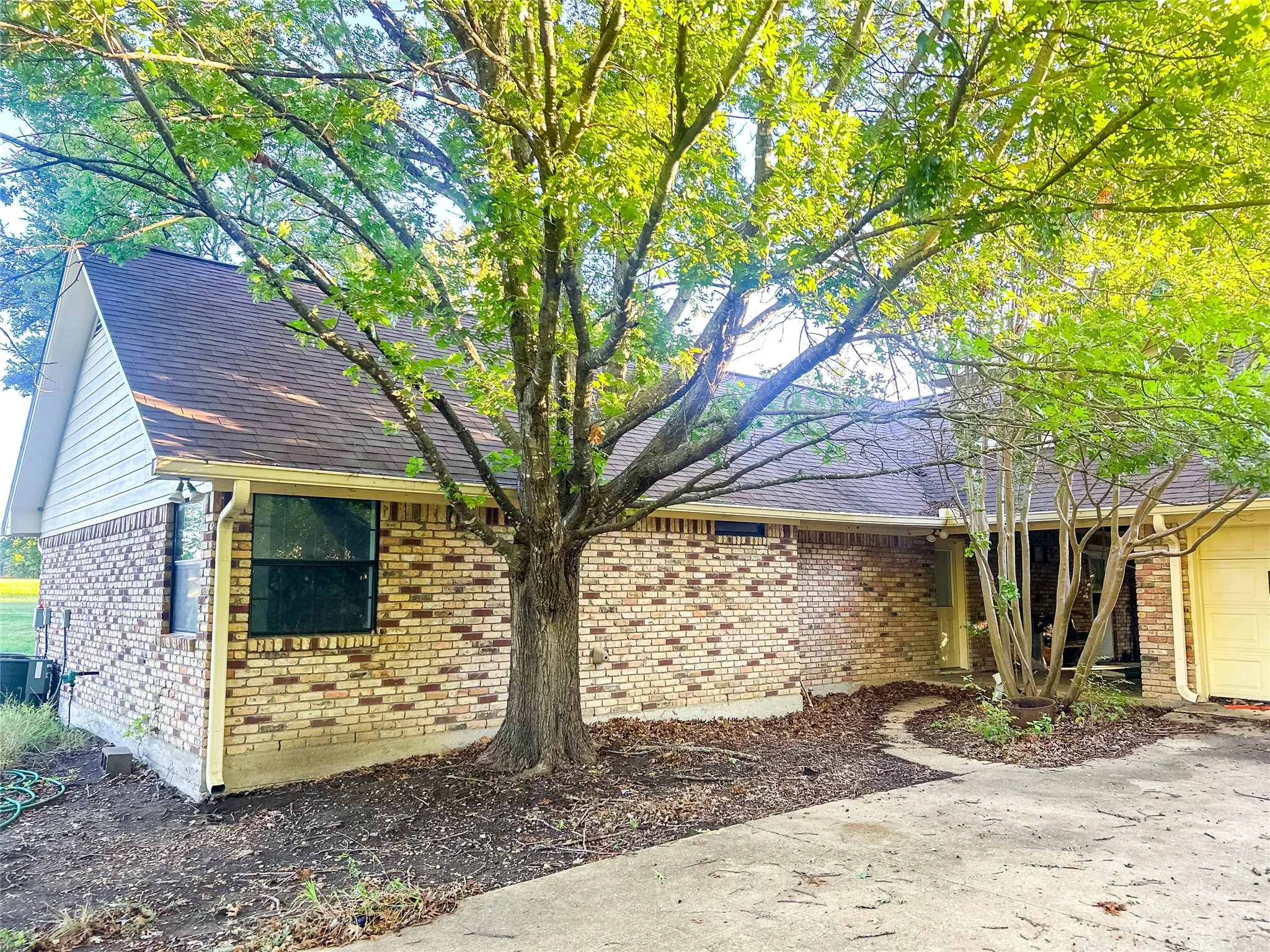 Brick exterior with horizontal siding gable, mature trees, and an attached garage