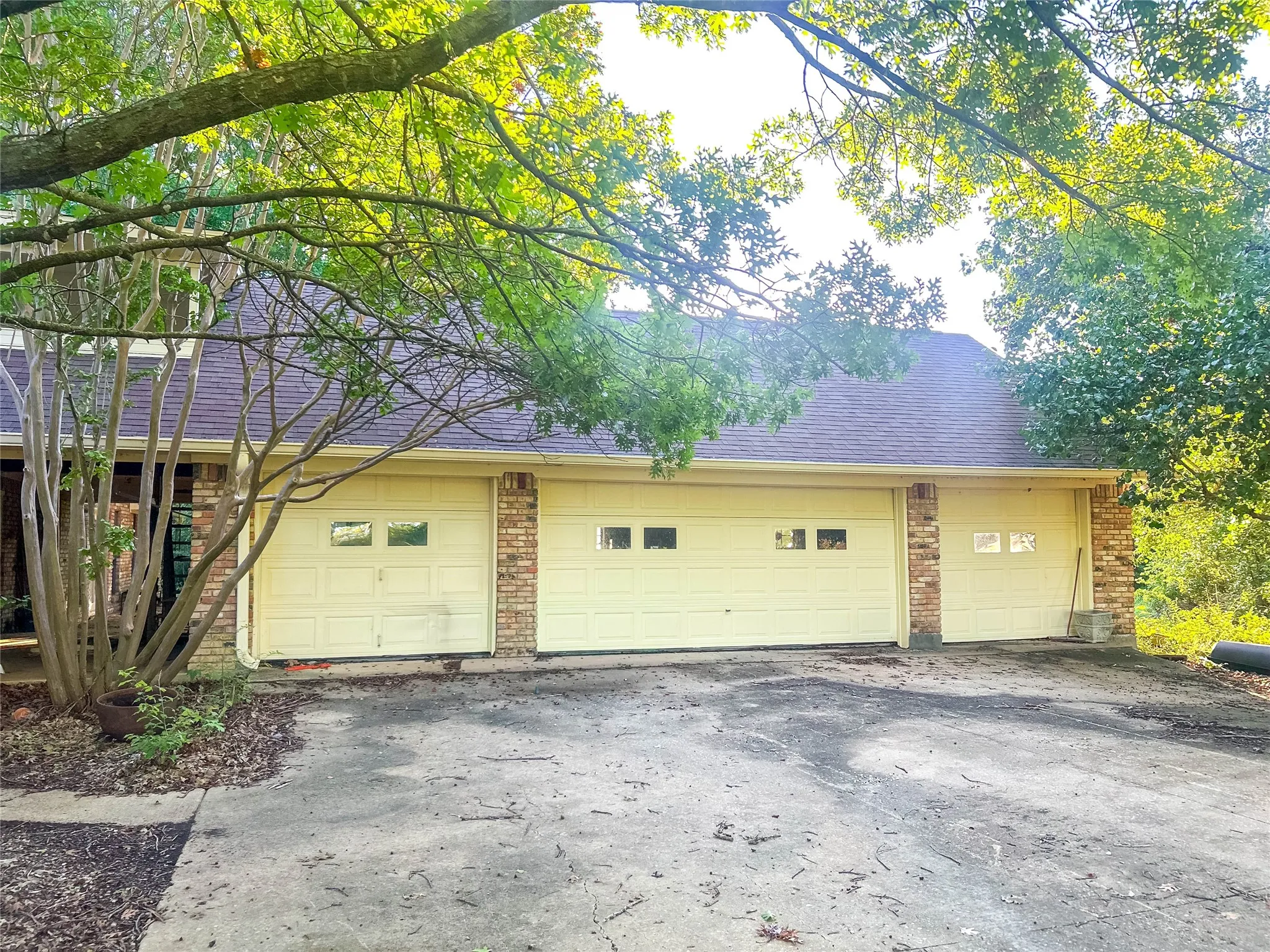 Three-car garage featuring panel doors with window inserts and brick accents
