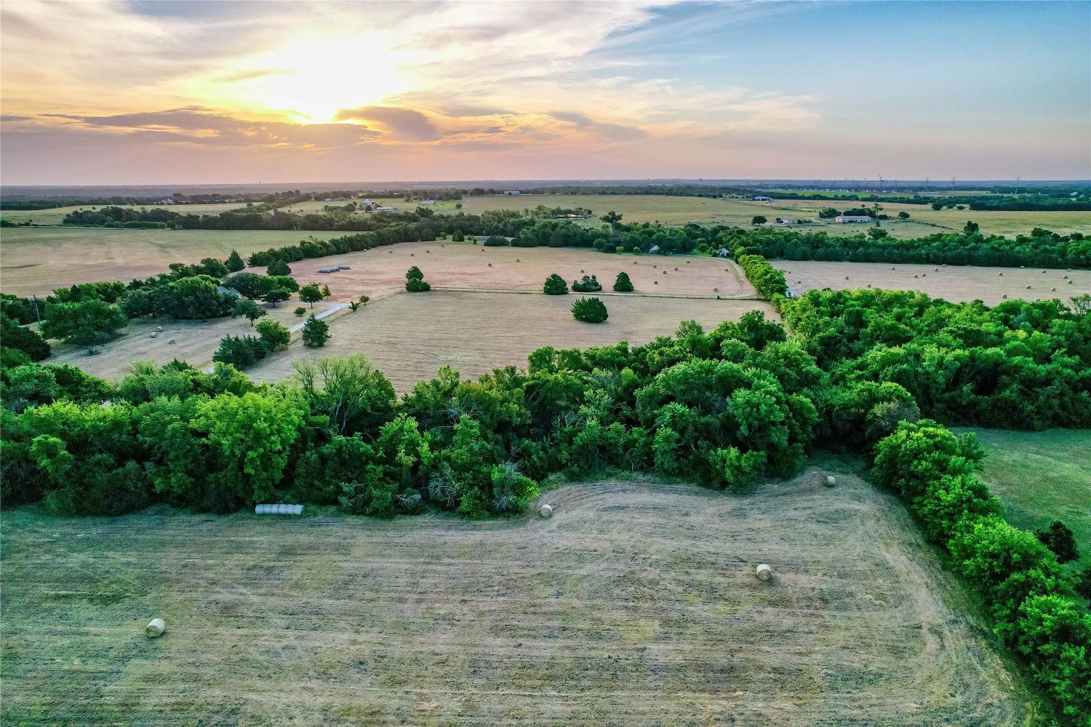 Expansive agricultural land featuring a diverse mix of cultivated fields and wooded areas