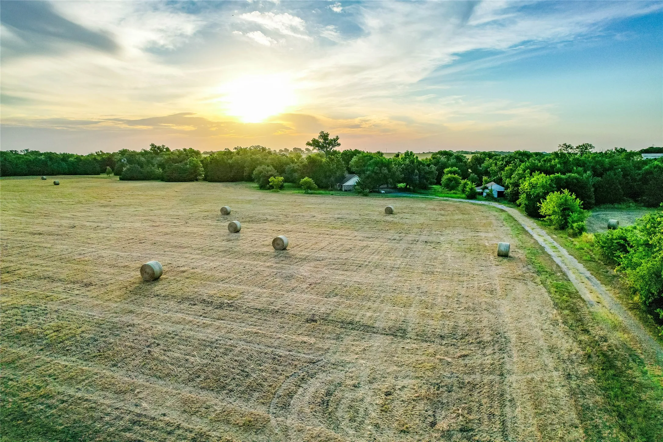 Expansive field with a natural tree line and visible structures
