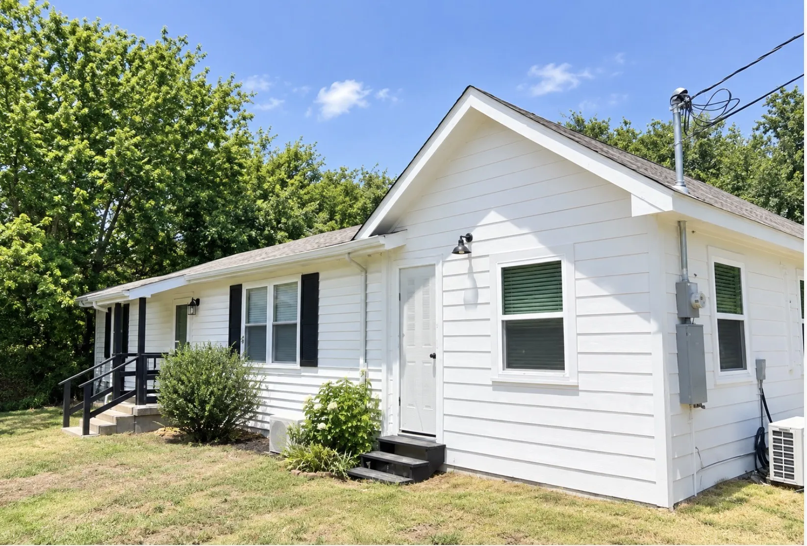 White horizontal siding exterior with dark shutters, dark trim, and a dark railing