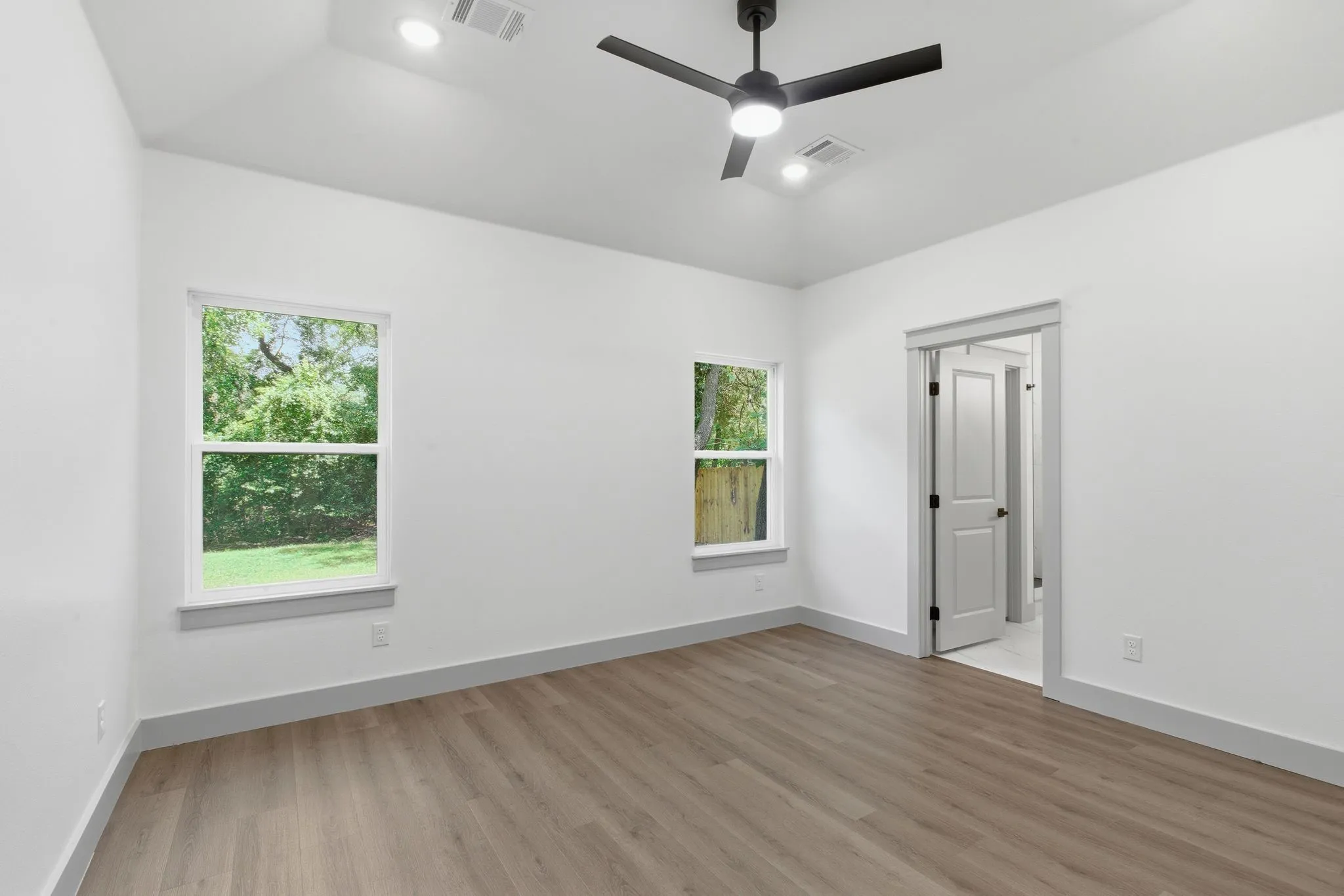 Vaulted ceiling, two windows, wood-finish flooring, modern ceiling fan, recessed lighting