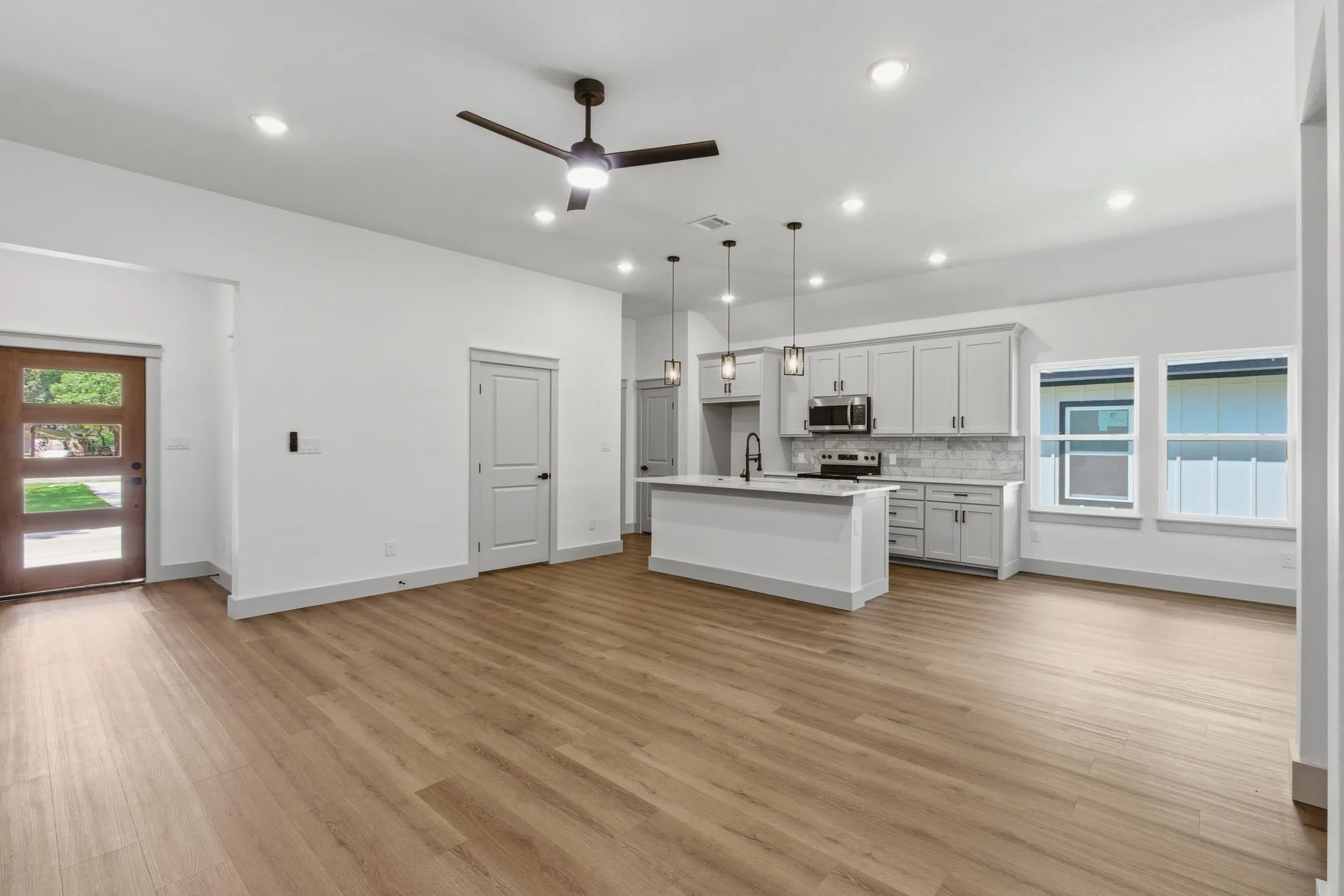 Open-concept living area with wood-finish flooring, recessed lighting, and a contemporary ceiling fan