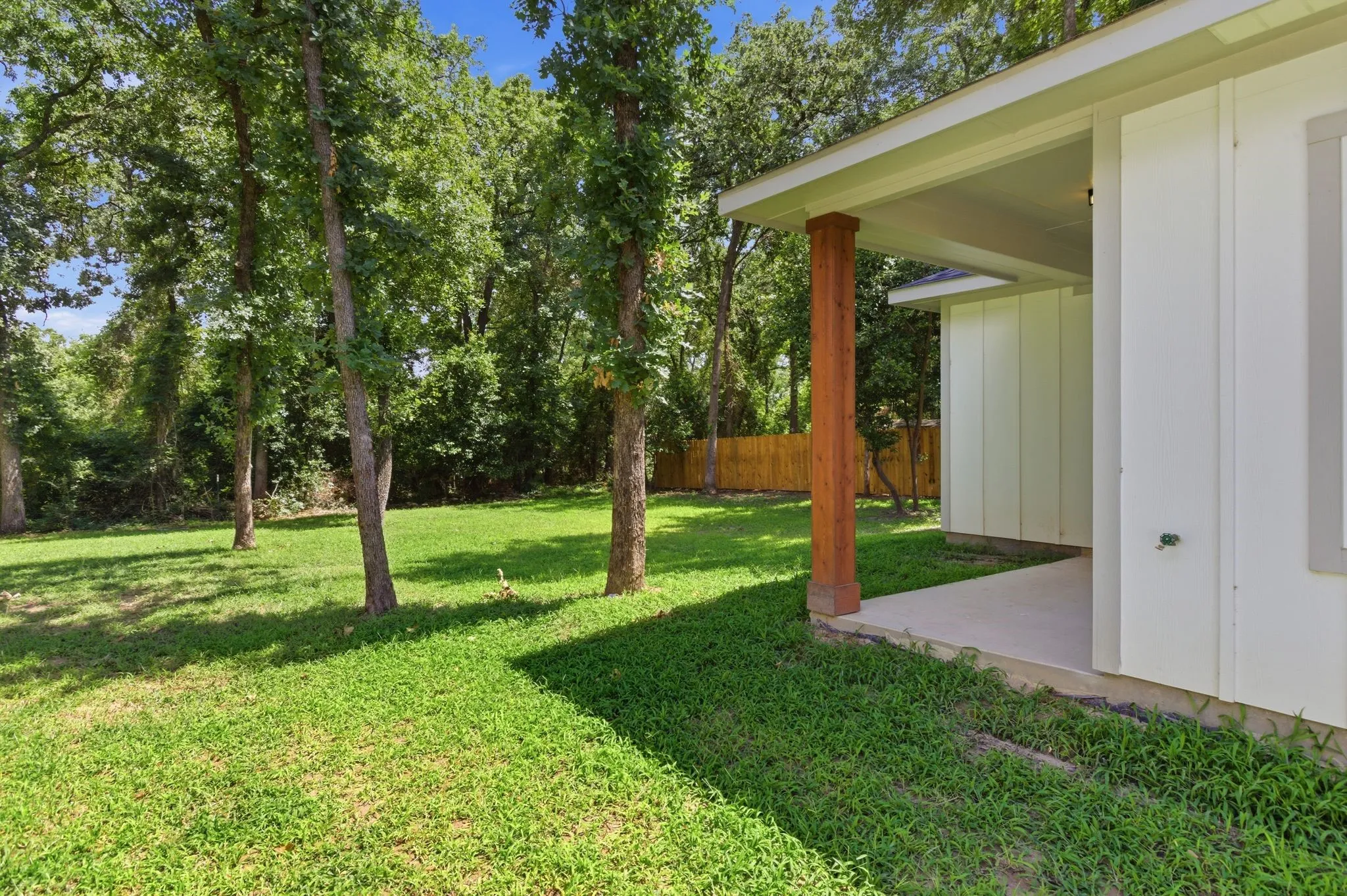 Expansive rear yard featuring mature trees and a manicured lawn