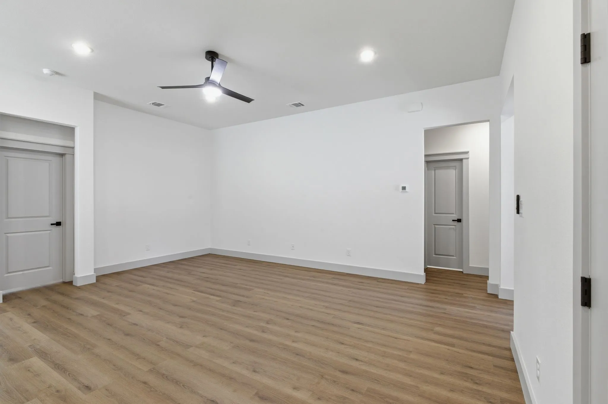 Spacious room featuring wood-finish flooring, recessed lighting, and a contemporary ceiling fan